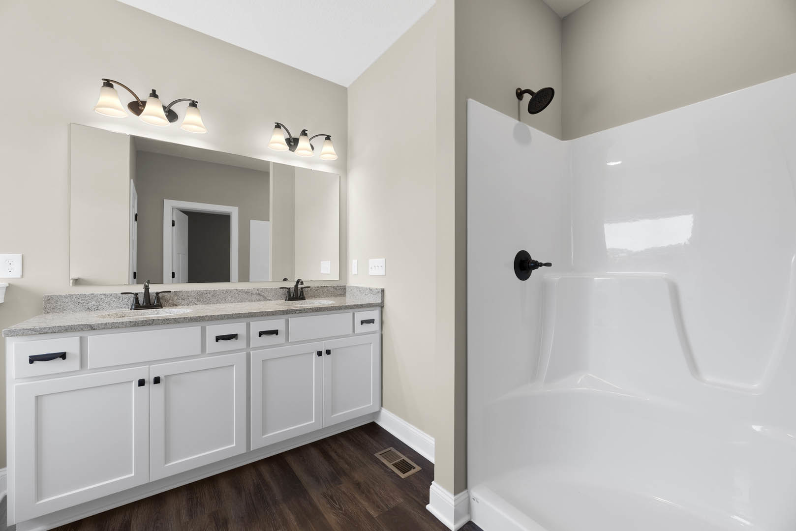 Bathroom with white tile shower, dual sinks set in light stone countertop, black faucets, white bathtub, wood vent cover, white door frame with black handle, wall-mounted shower