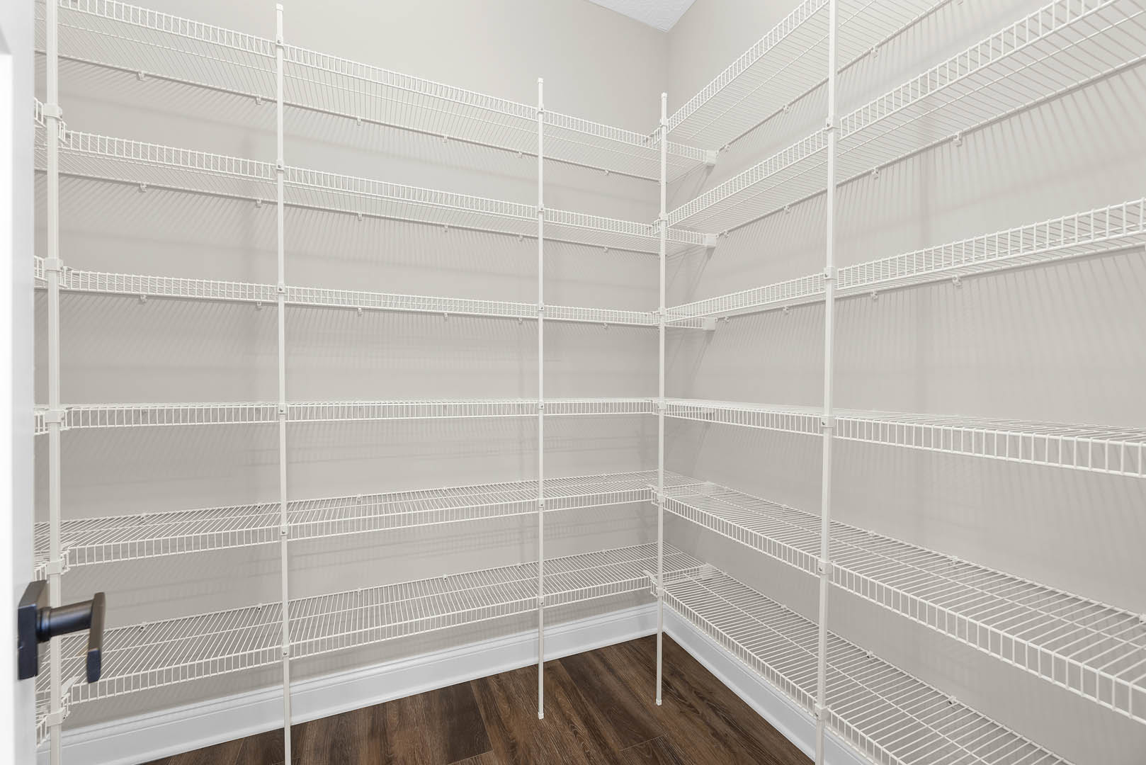 White built-in shelves against a light wall, wood flooring with white baseboard trim, black metal bar detail visible in foreground.