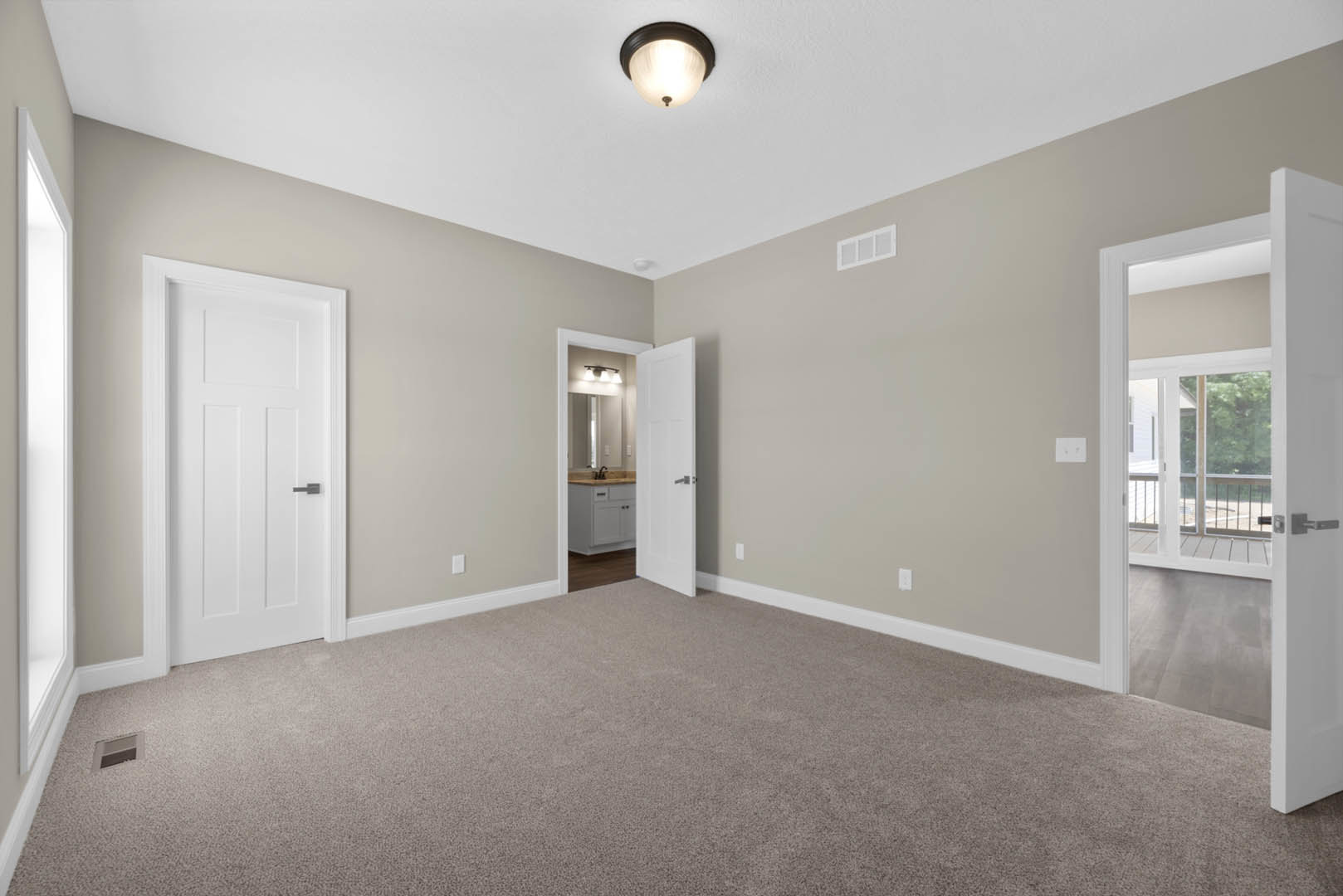 Carpeted room with white doors featuring black handles, white rectangular window with trim, ceiling light fixture, and grey rectangular object on a white surface