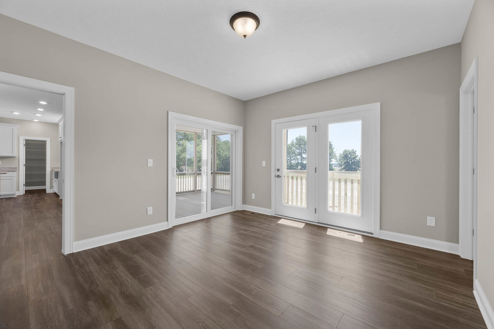 Hardwood floor room with double glass-paneled doors, white framed door, sliding glass door opening to porch, ceiling light fixture, plaster walls