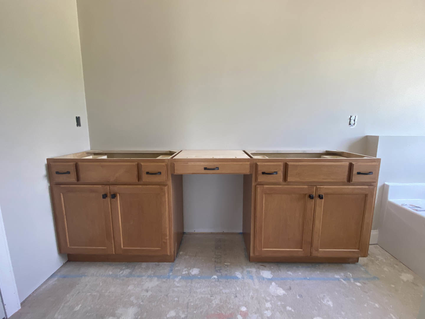 White quartz kitchen countertop with built-in stainless steel sink, light wood cabinetry, and drawers, set against a neutral wall and light tile flooring.