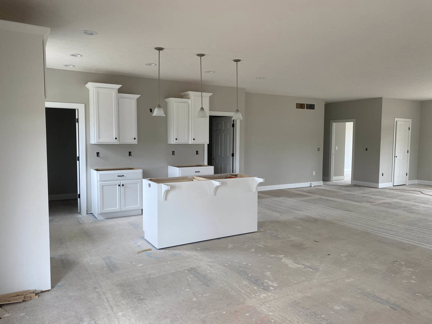 Modern kitchen with white countertop, open shelving, white cabinetry with drawers, white walls accented by black borders, and white doors featuring black handles and a light switch