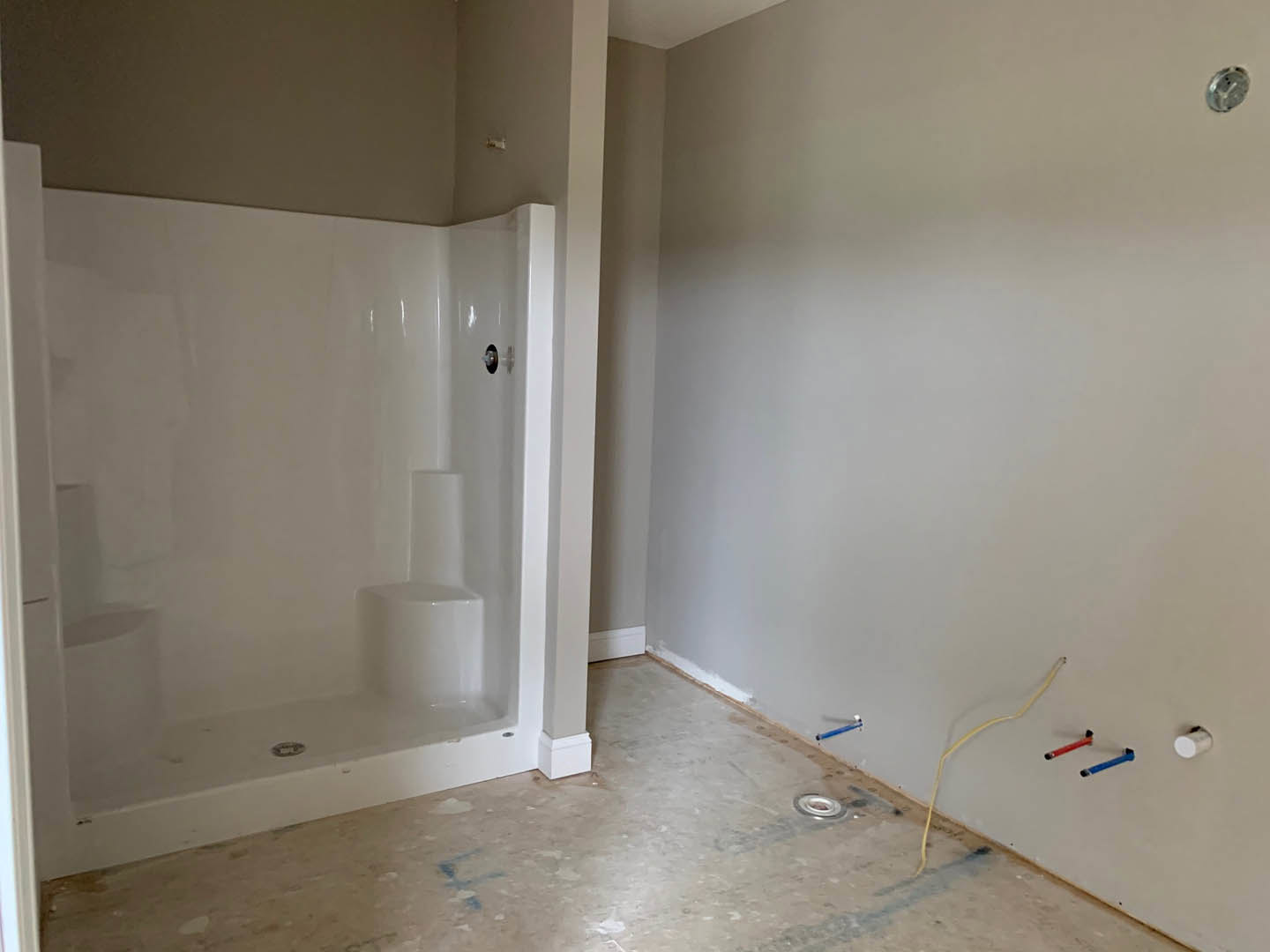 Modern bathroom featuring a glass-enclosed shower, freestanding white bathtub, light-colored tile flooring, white plaster walls, and a wall-mounted clock.