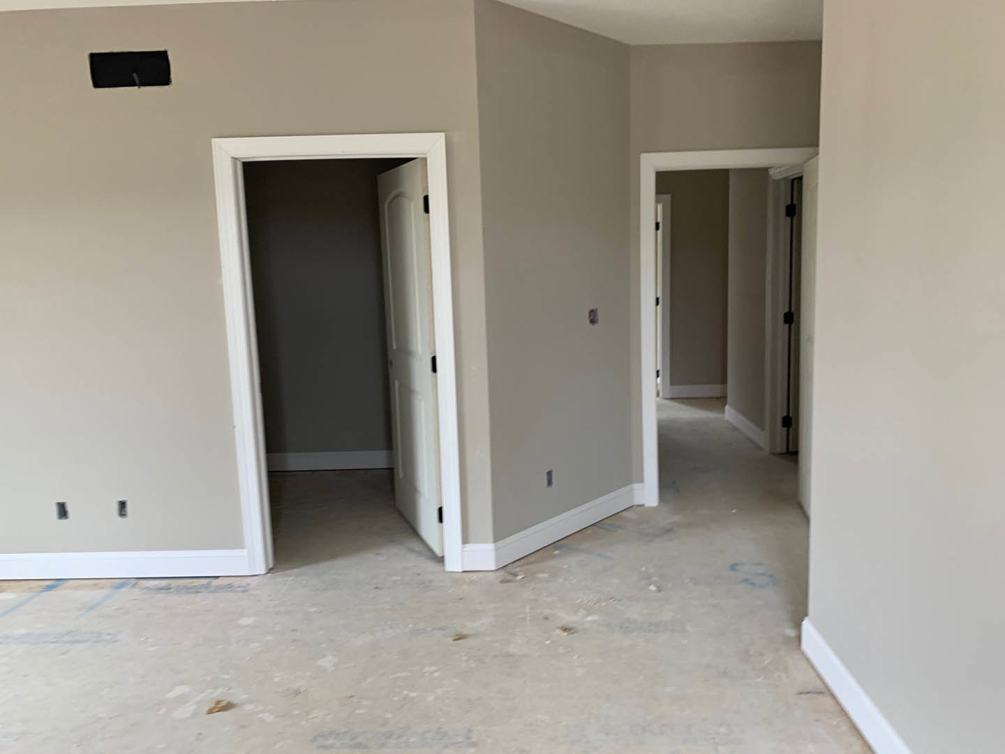 White walls and white door with black handle and hinges, smooth plaster finish, light flooring, minimal modern interior