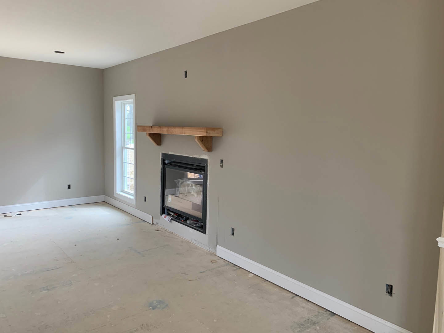 Living room with plaster walls, white-framed window, glass door, exposed wooden beam, and built-in fireplace on light flooring