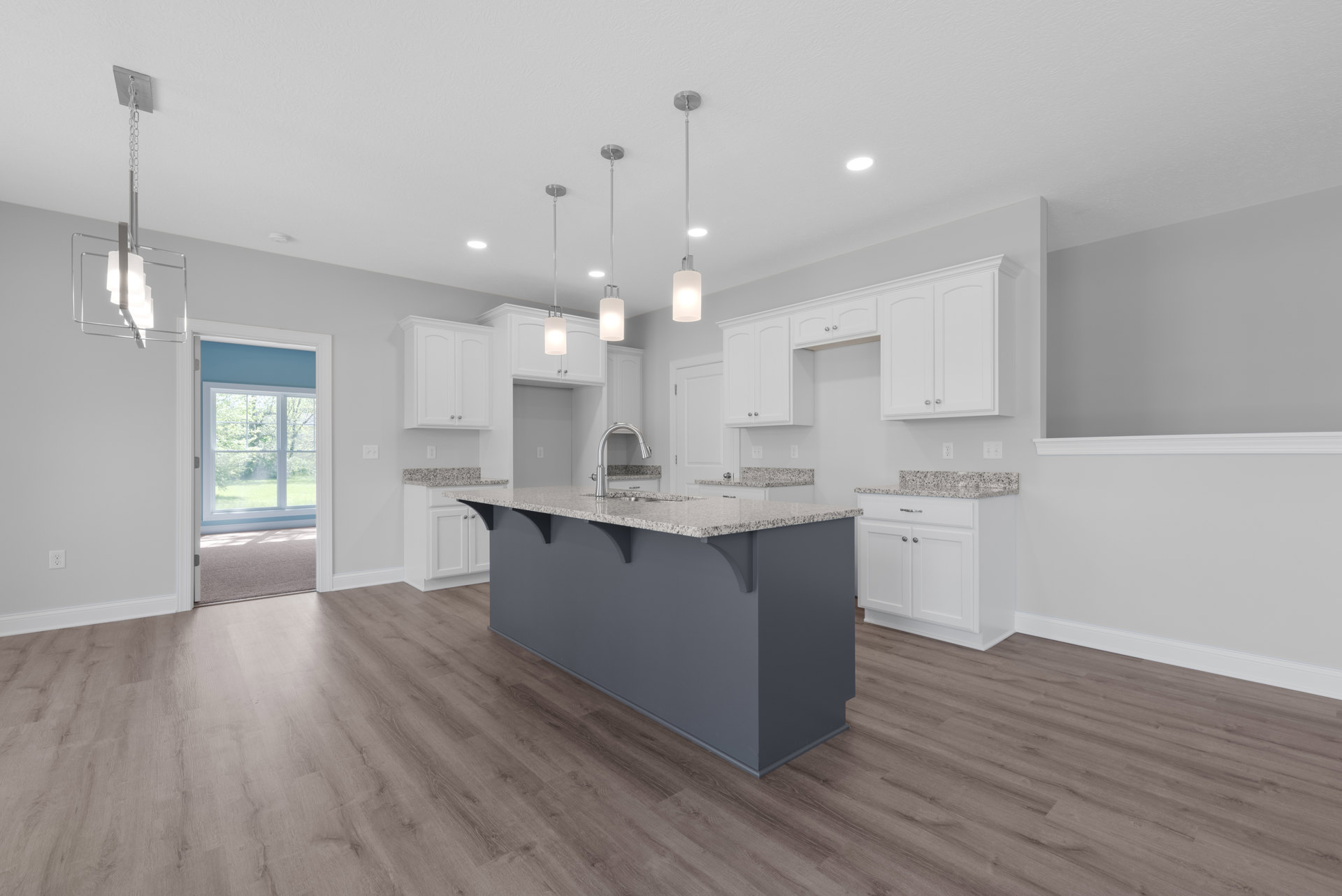 Kitchen featuring a central island with granite countertops, white cabinetry, wood flooring, large window overlooking outdoors, and pendant lighting.