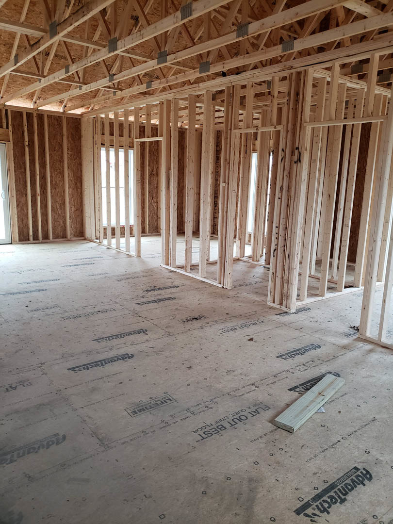 Exposed wood ceiling beams, unfinished walls, large window, construction materials on floor