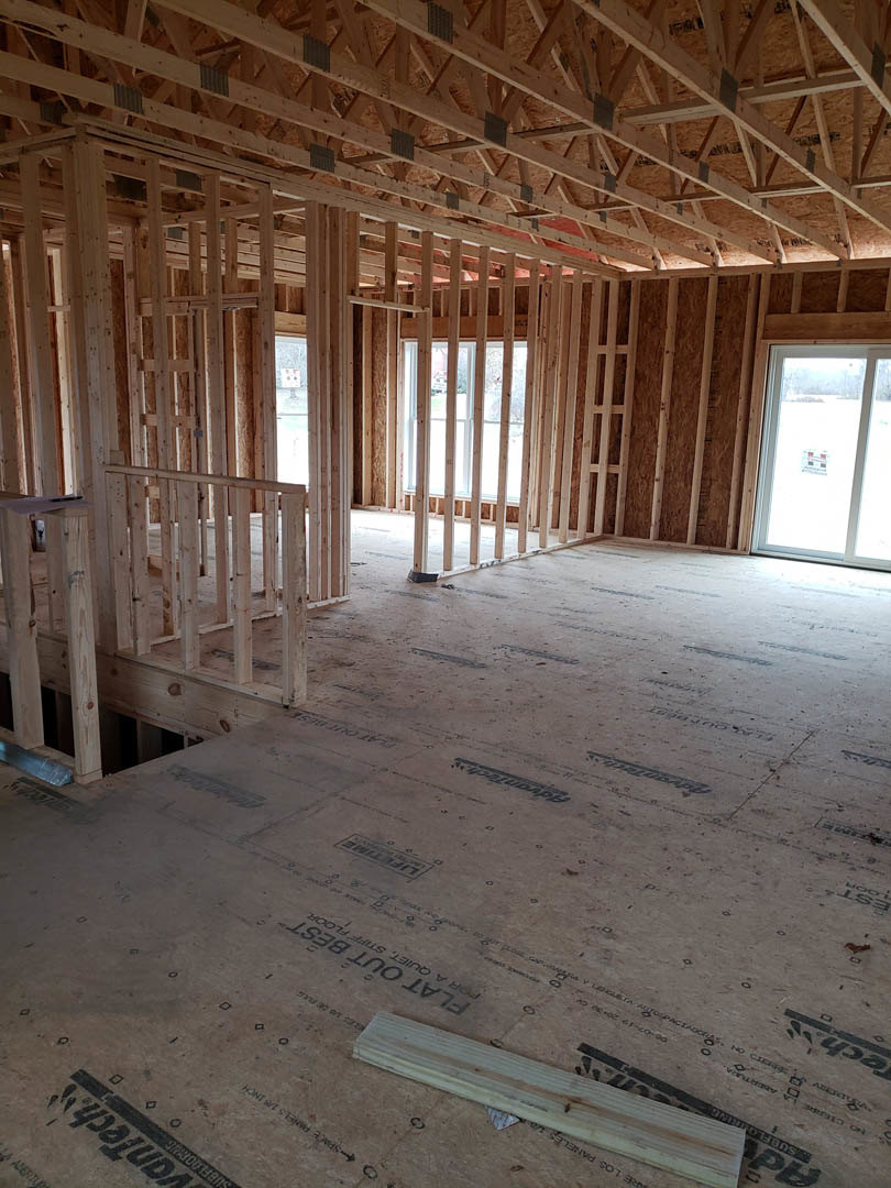Living room with exposed wood ceiling beams, large window, and light-colored walls