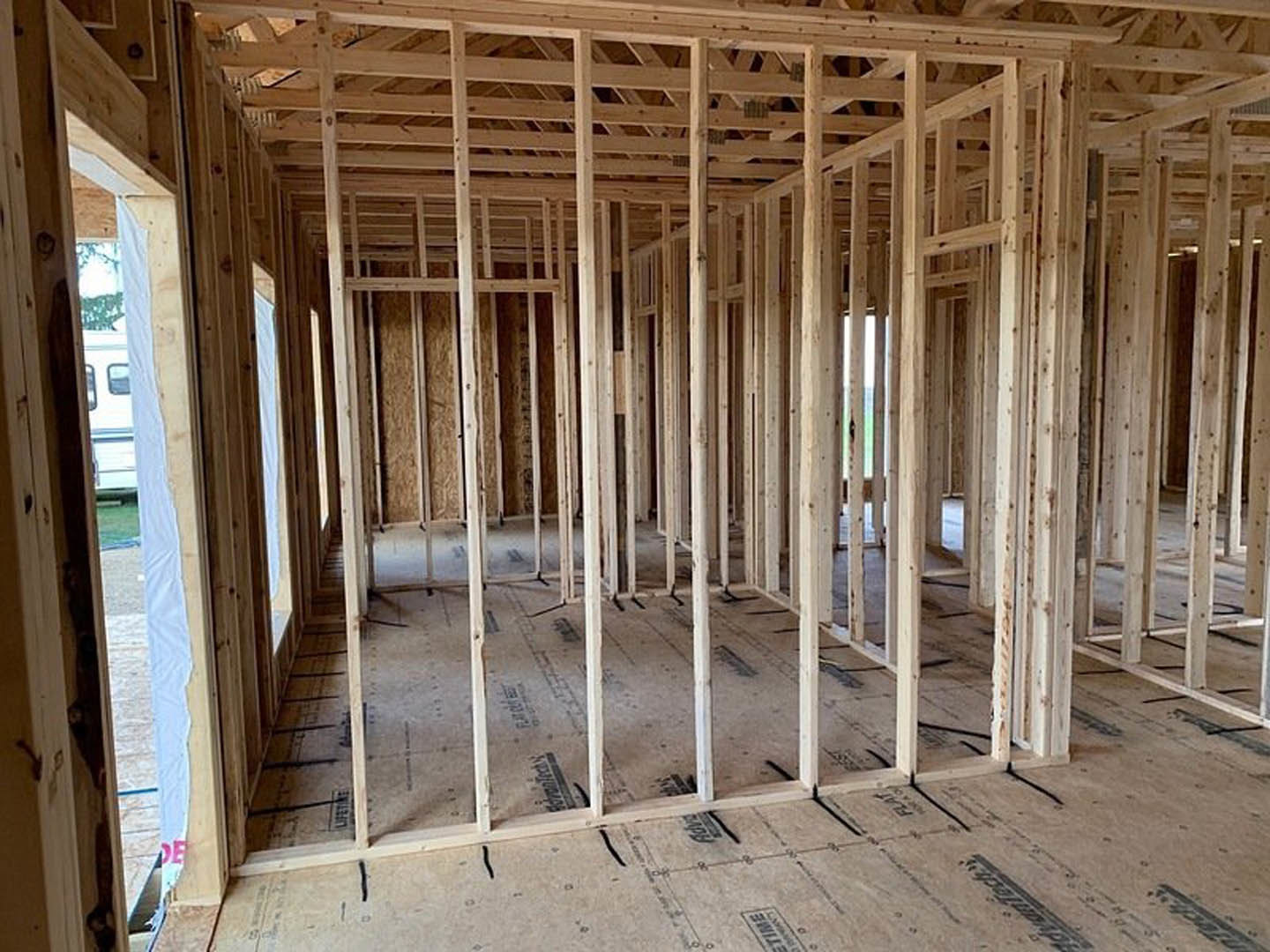 Wood framing with exposed beams and planks, unfinished interior walls, construction materials visible, window opening in progress