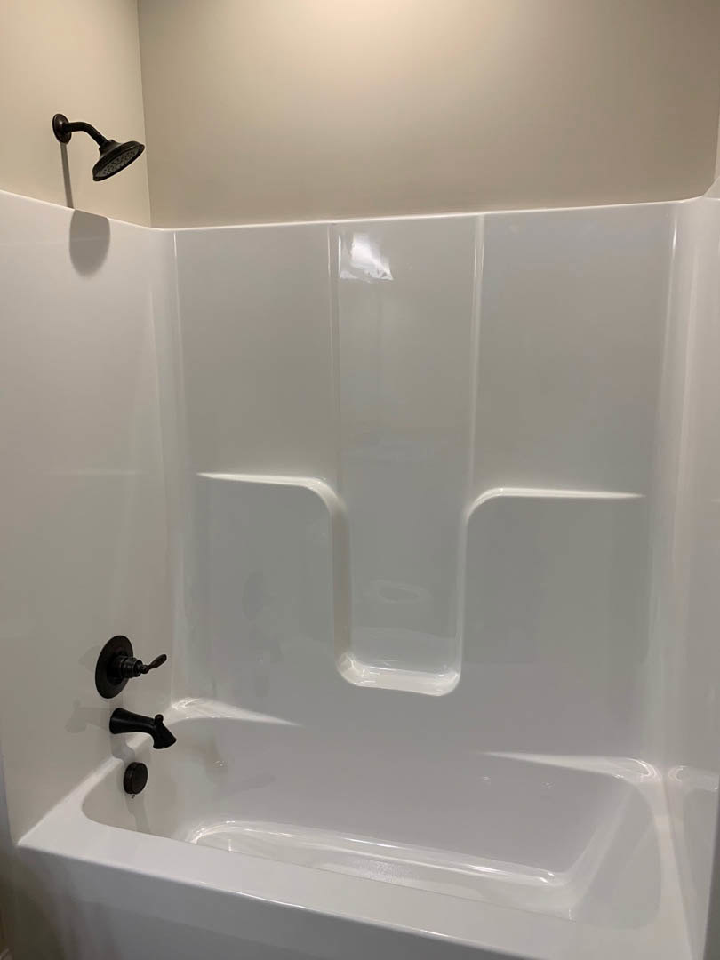 White bathtub with matte black shower head and fixtures against white tiled bathroom wall