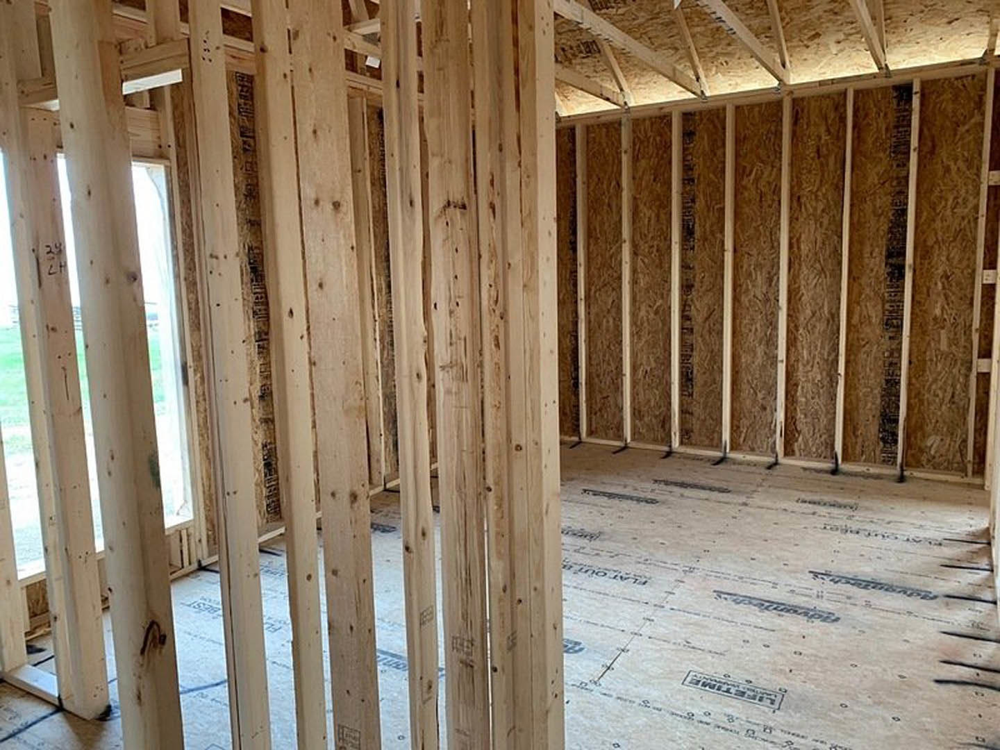 Living room with exposed wood ceiling beams, large window, and light-colored walls
