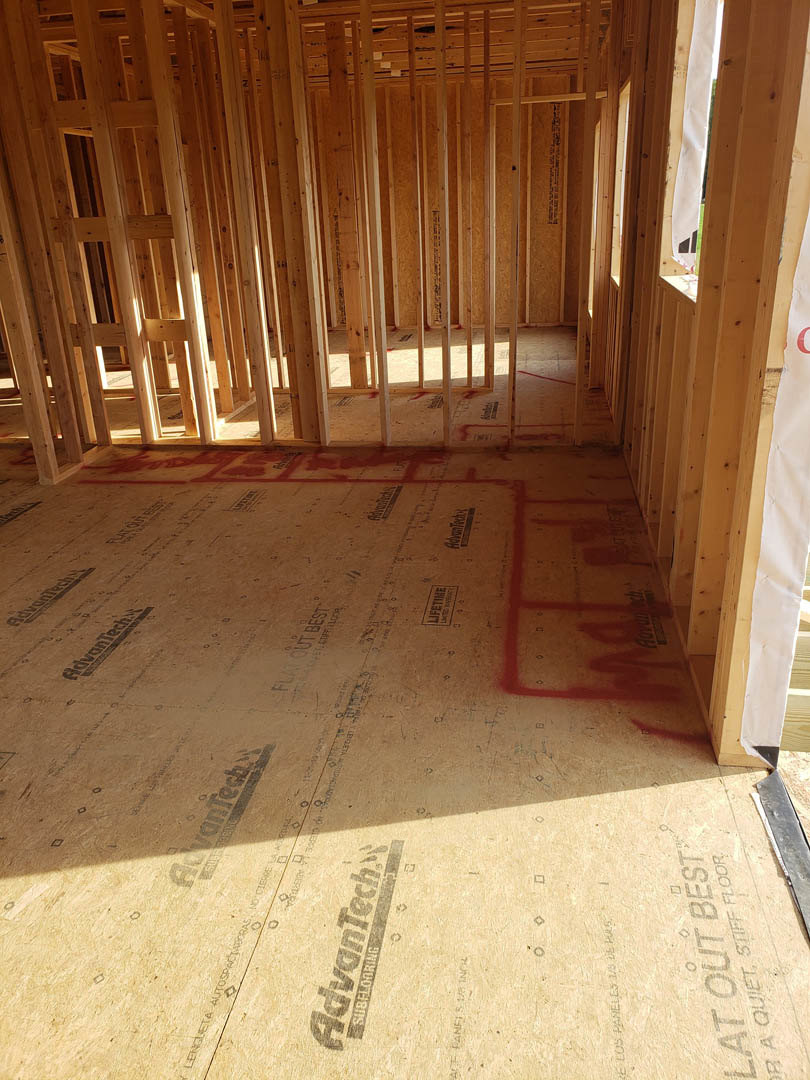 Wood-framed room with exposed beams, red painted walls, hardwood flooring, and natural light highlighting construction details