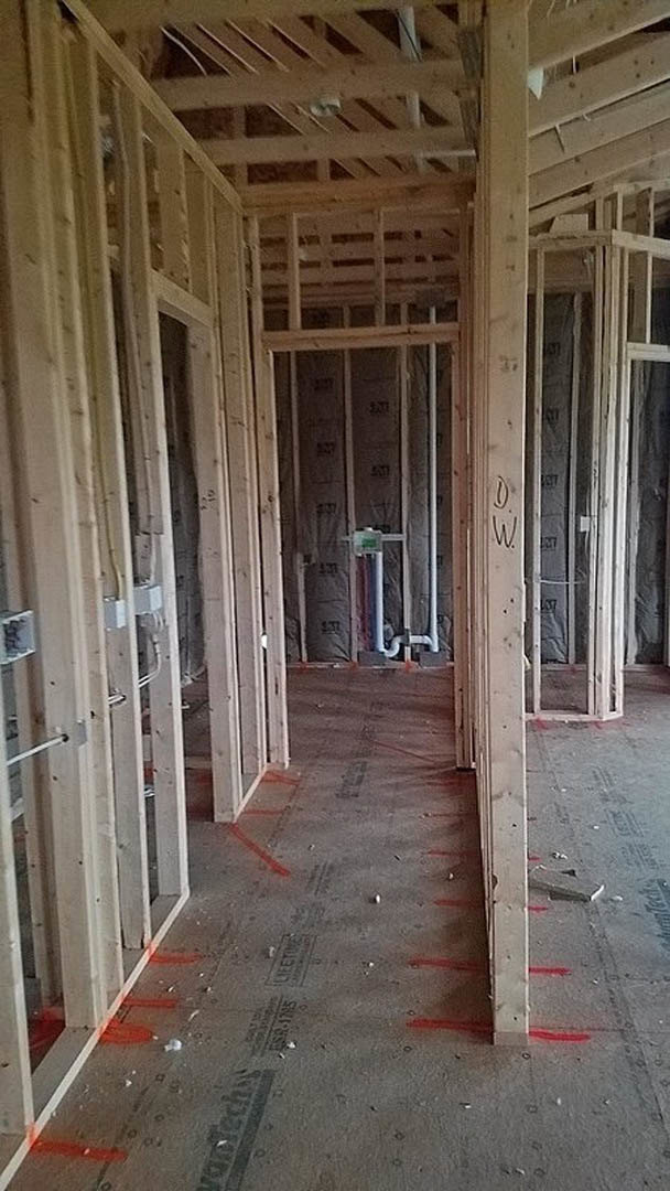 Unfinished interior room with exposed wood framing, ceiling beams, wall studs, and partially installed insulation
