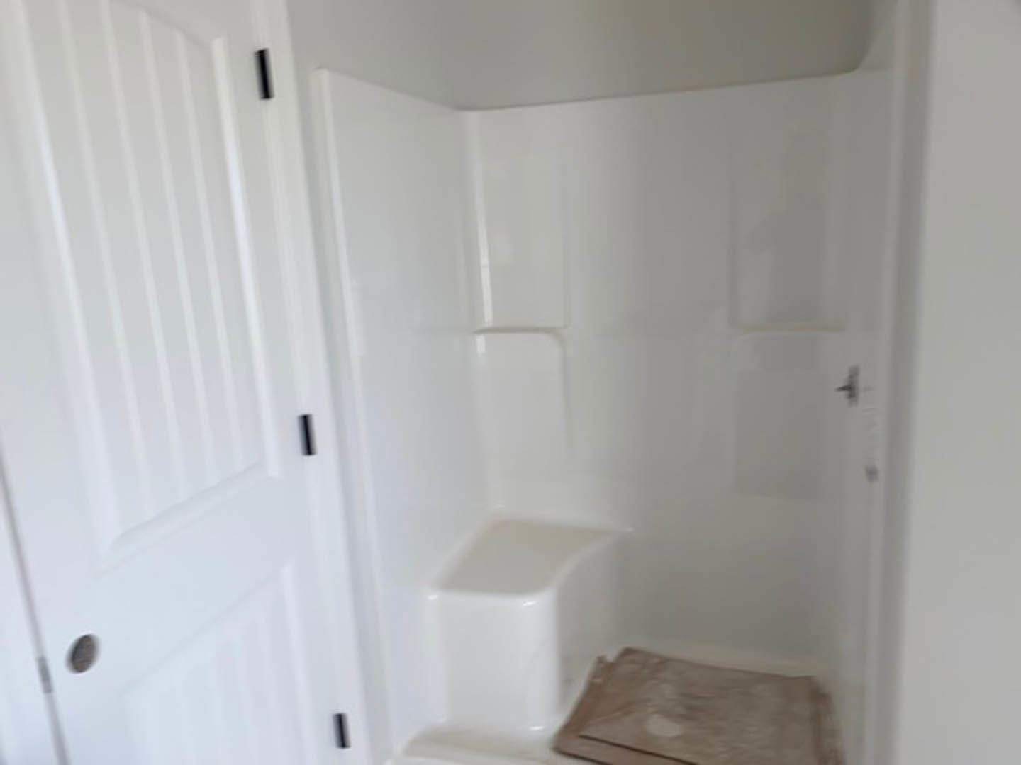 White tiled shower with built-in seat, small rug in corner, adjacent to white bathtub and toilet in modern bathroom.