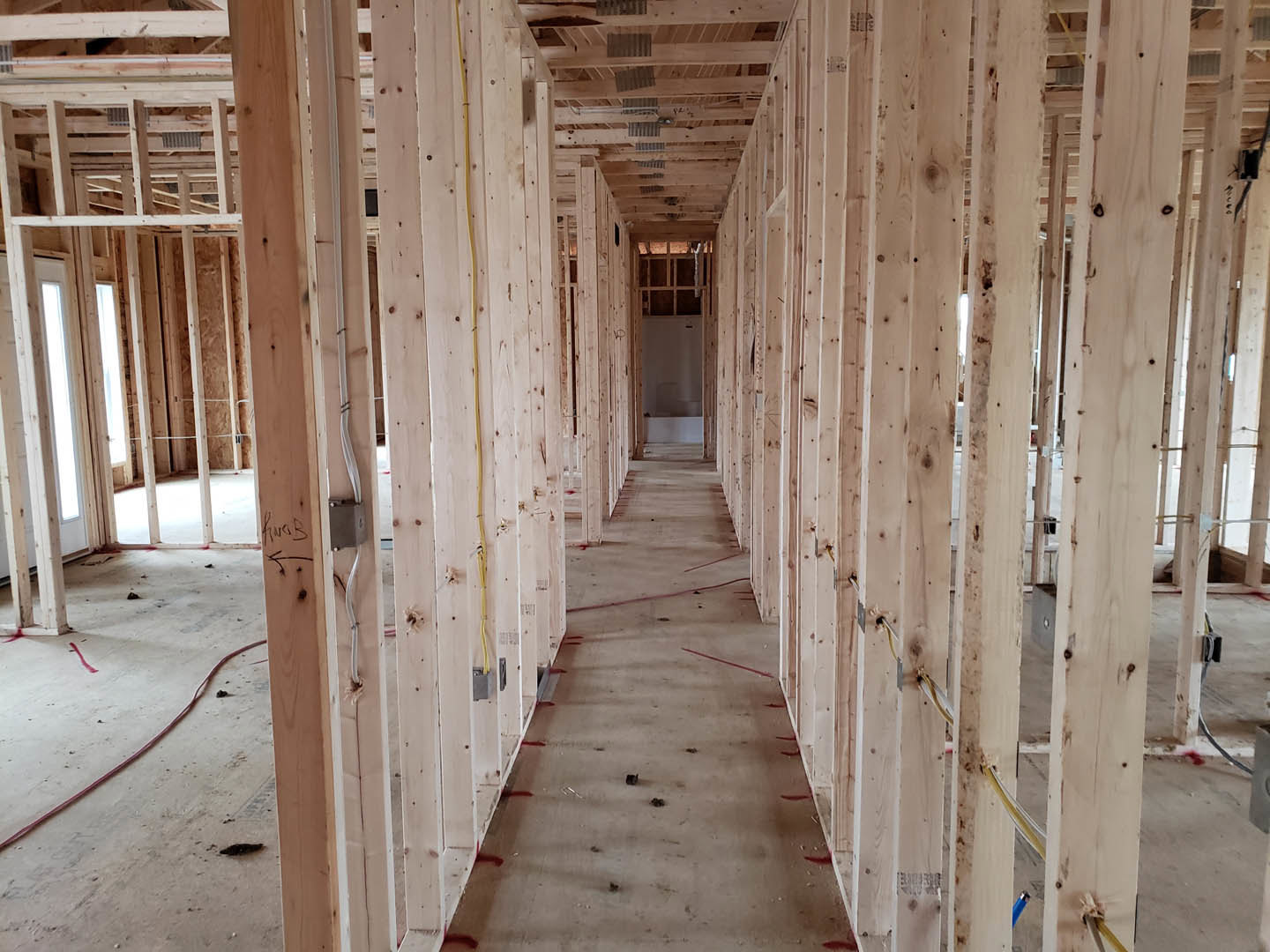 Long hallway with exposed wood beams and metal ceiling panels, light-colored walls, and hardwood flooring