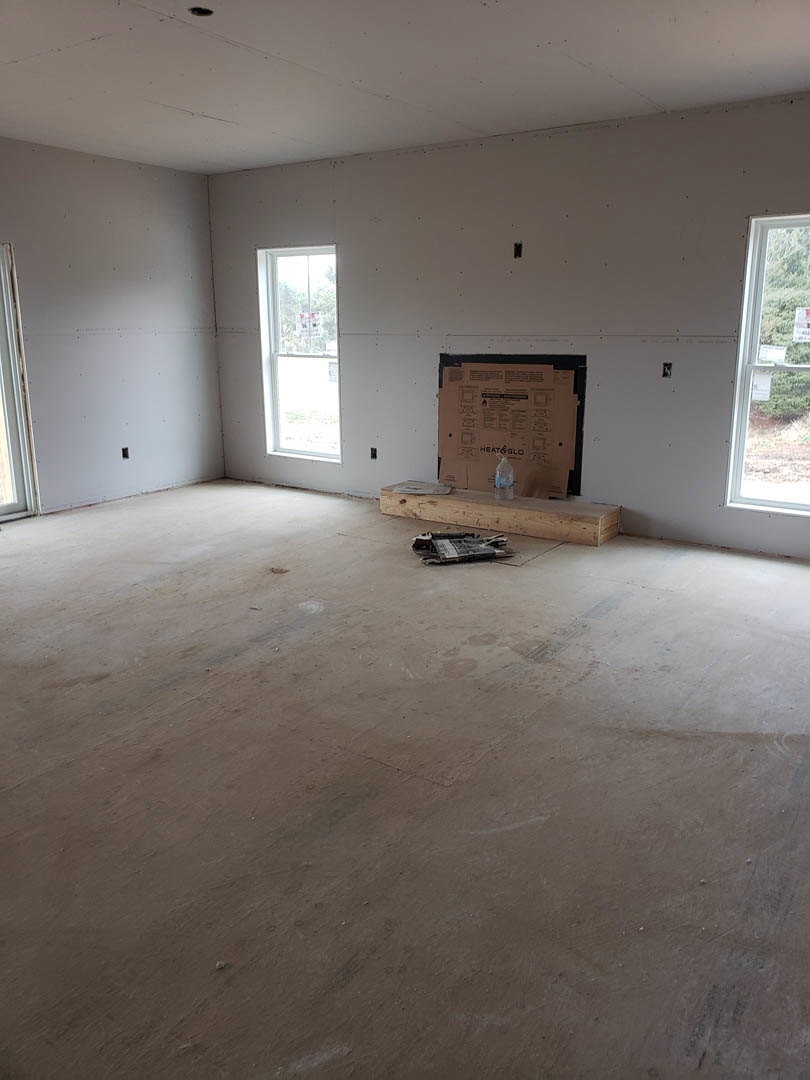 Wood floor room with white plaster walls, large window displaying signs, cardboard box and water bottle placed near window.