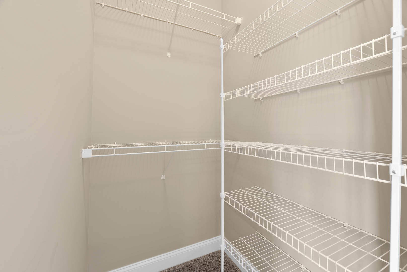 White wire shelving unit mounted on a wall in a room, featuring metal clips and horizontal white bars.