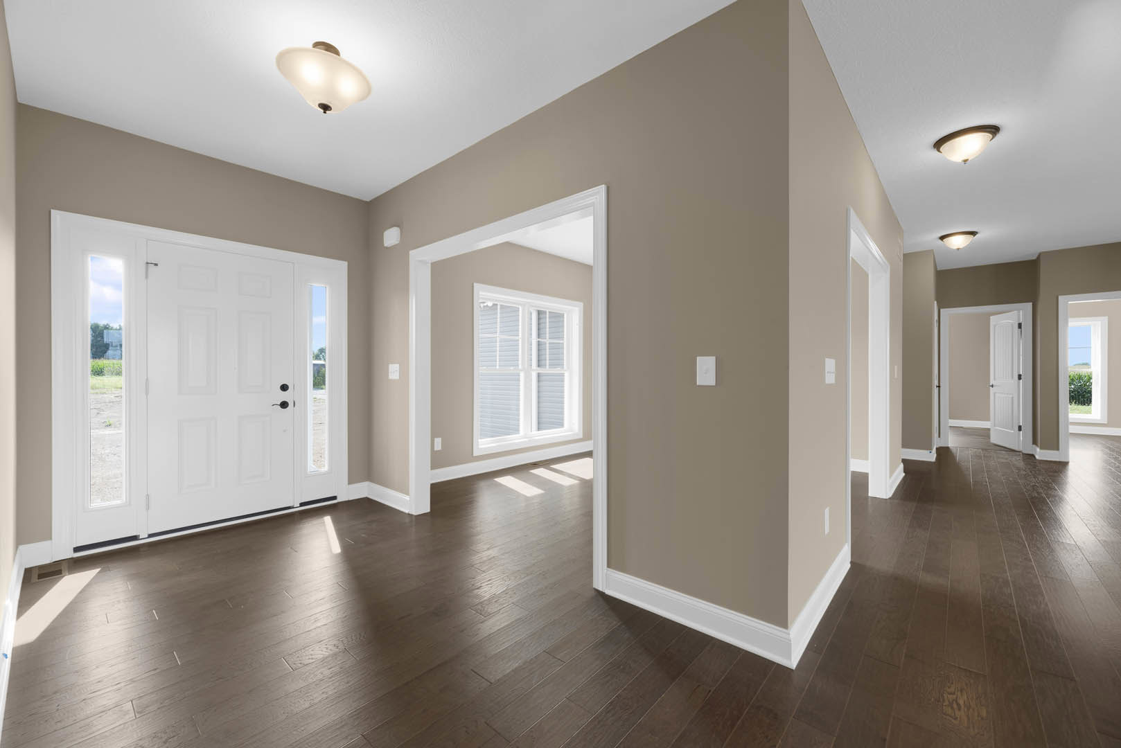 Hallway with white paneled doors, wood flooring, white plaster walls, and ceiling; glass window inset in one door; modern light fixture overhead.