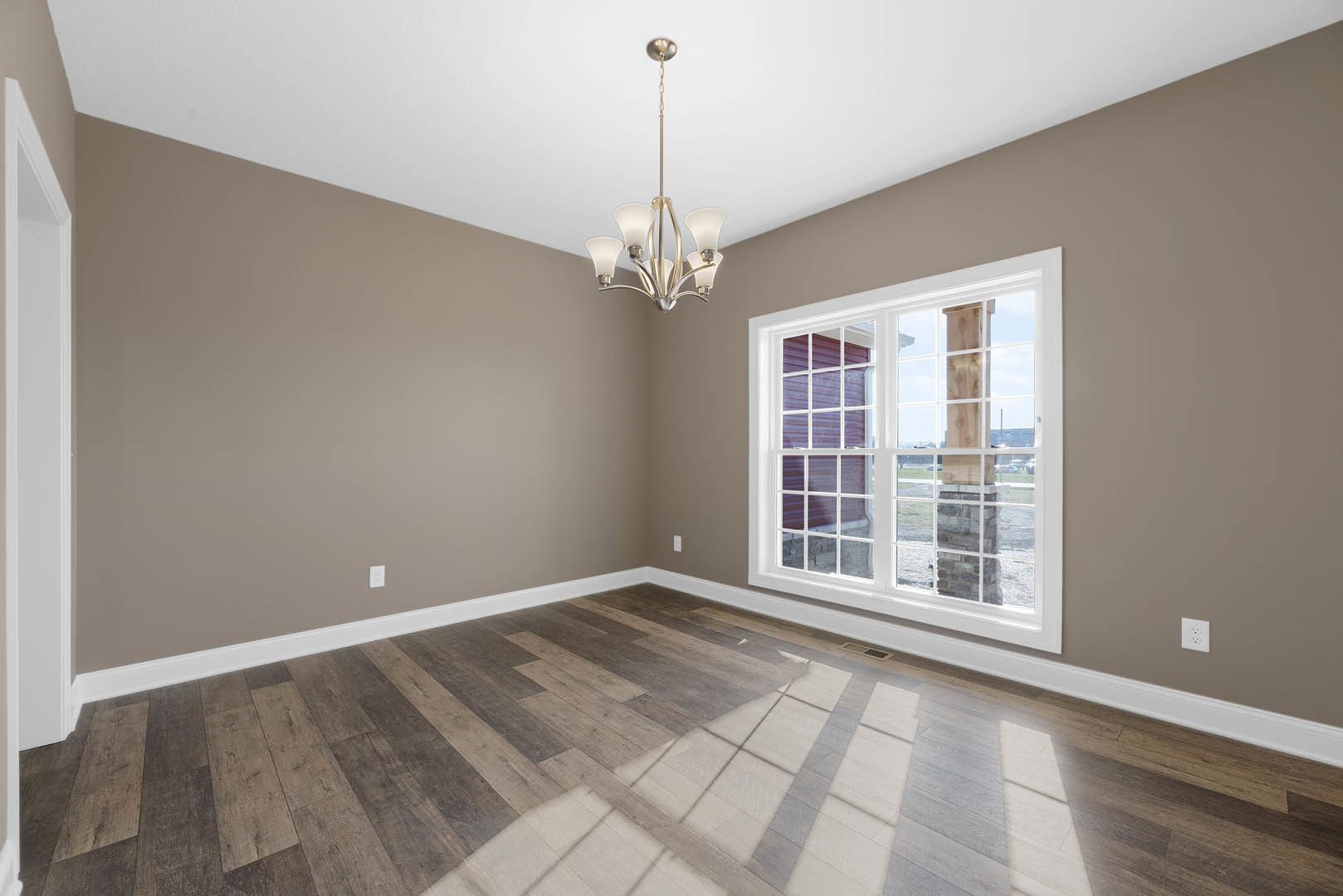 Wood flooring room with white-framed window, plaster walls, decorative molding, and crystal chandelier