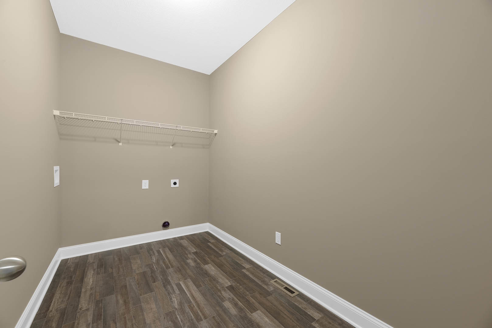 Wood floor with white baseboards, white plaster walls, and smooth white ceiling in a residential interior space