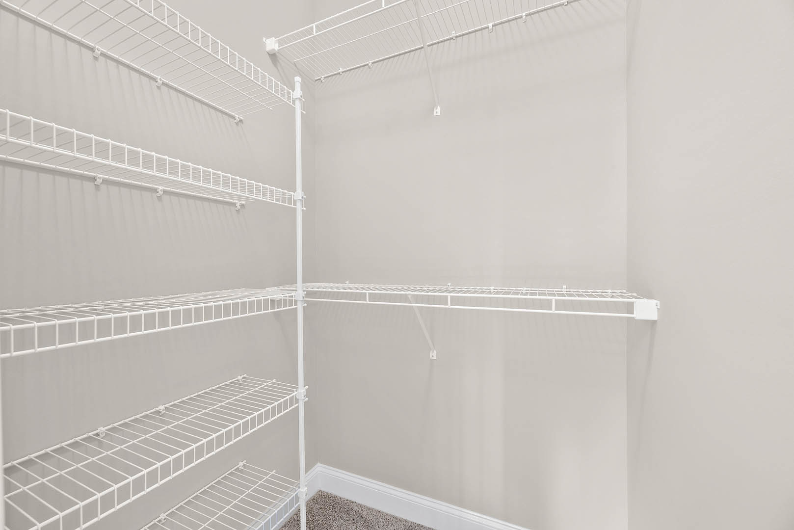 White metal wire shelving unit mounted on a white wall in a minimalist room