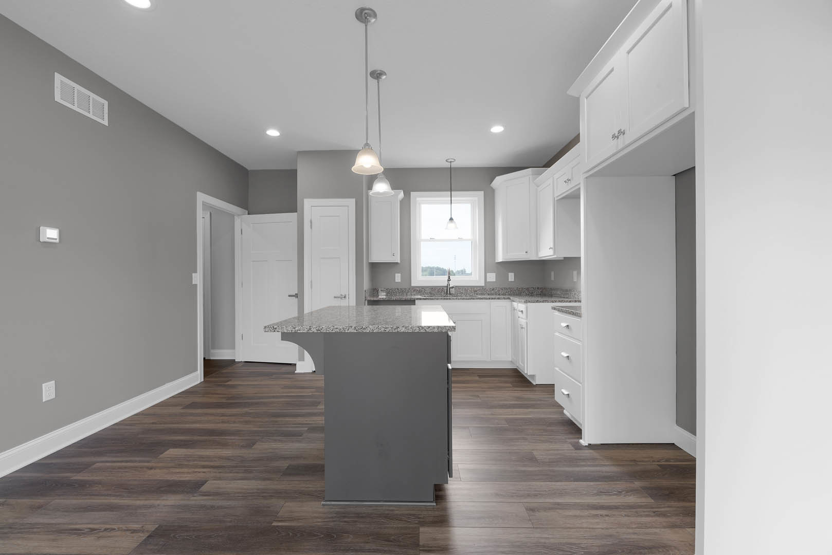 White kitchen cabinets, marble island countertop, stainless sink, pendant light fixtures, tile flooring, large window with natural light, wall vent