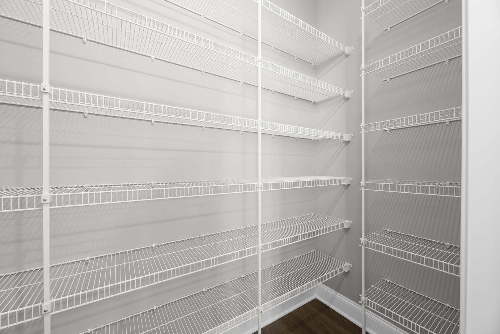 White wire shelving mounted on a gray wall above wood flooring in a residential room.