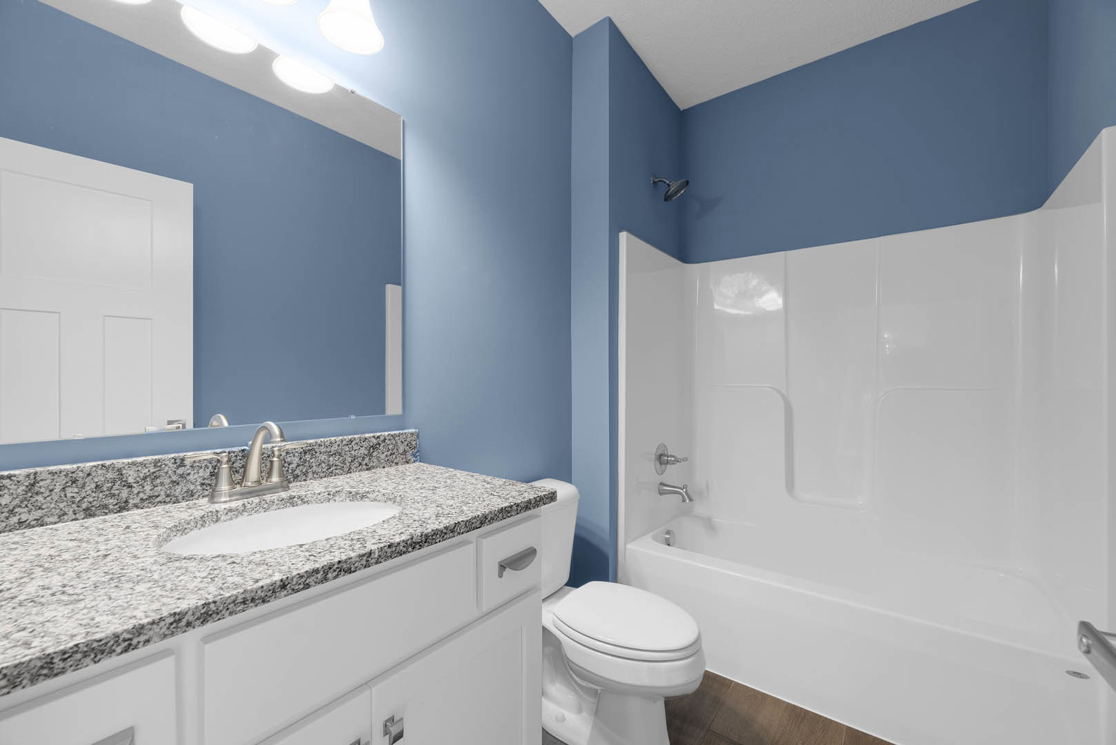 Bathroom with white bathtub, modern sink on stone countertop, white toilet, tiled walls, and three-panel white door