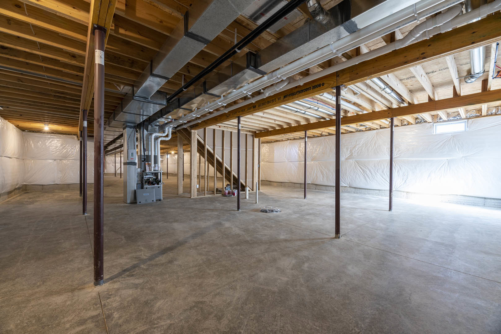Wooden ceiling with exposed metal pipes, concrete floor featuring a circular object, metal beams along walls, industrial-style interior.