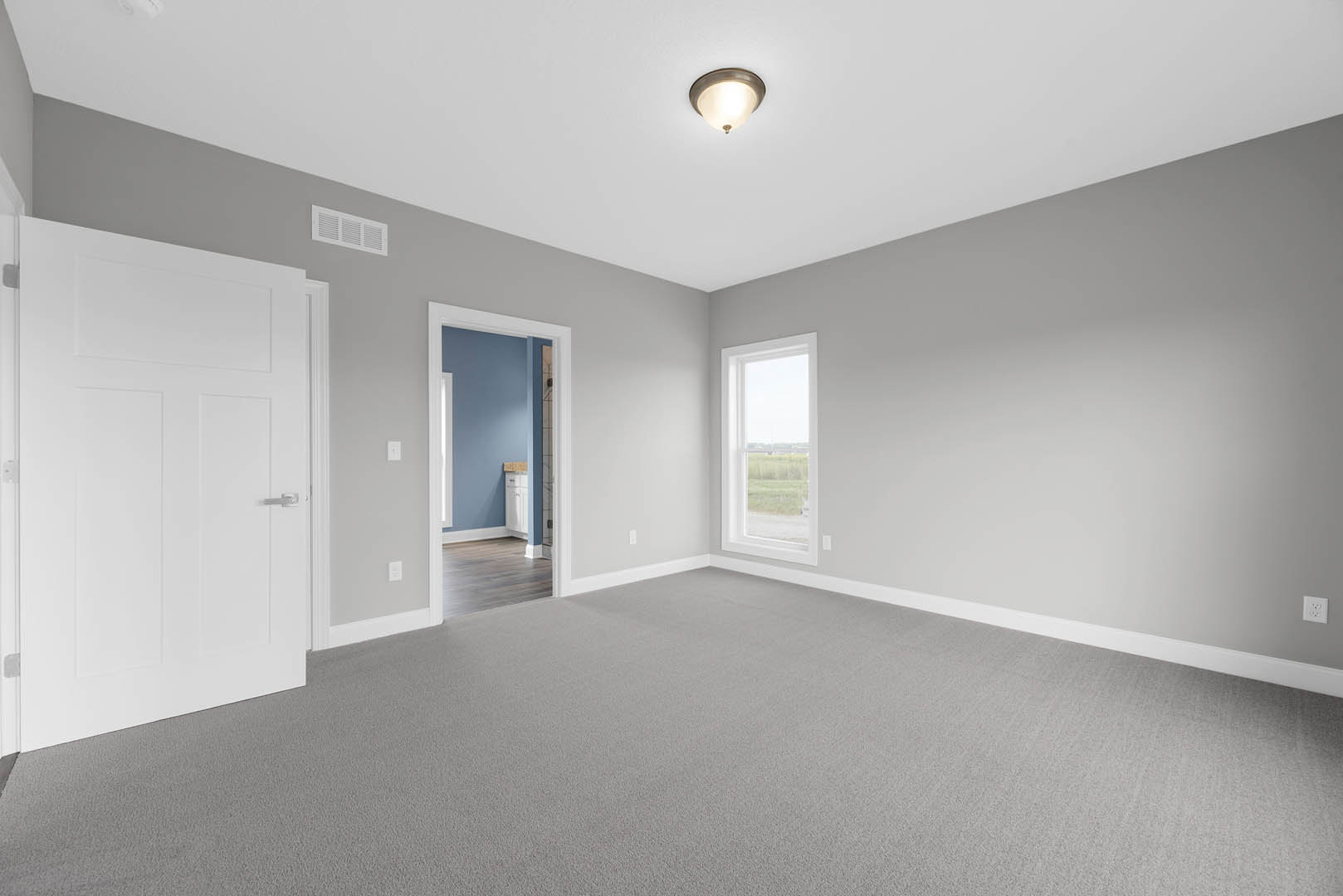 Blue accent wall with white cabinets, white door with silver handle, ceiling light fixture, window overlooking grassy field, carpeted floor
