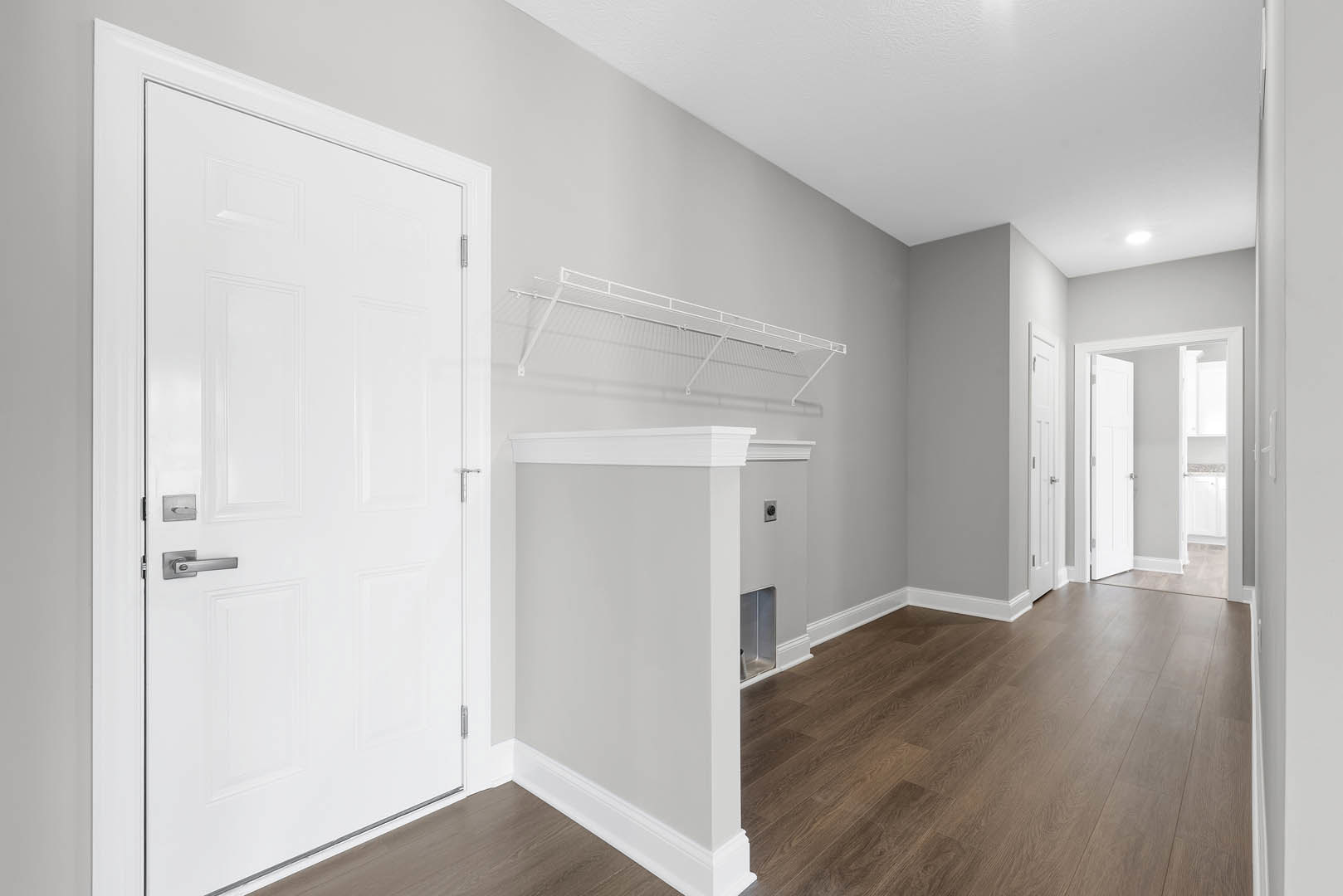 Hallway with white paneled doors, white walls, white railing, and light wood laminate flooring