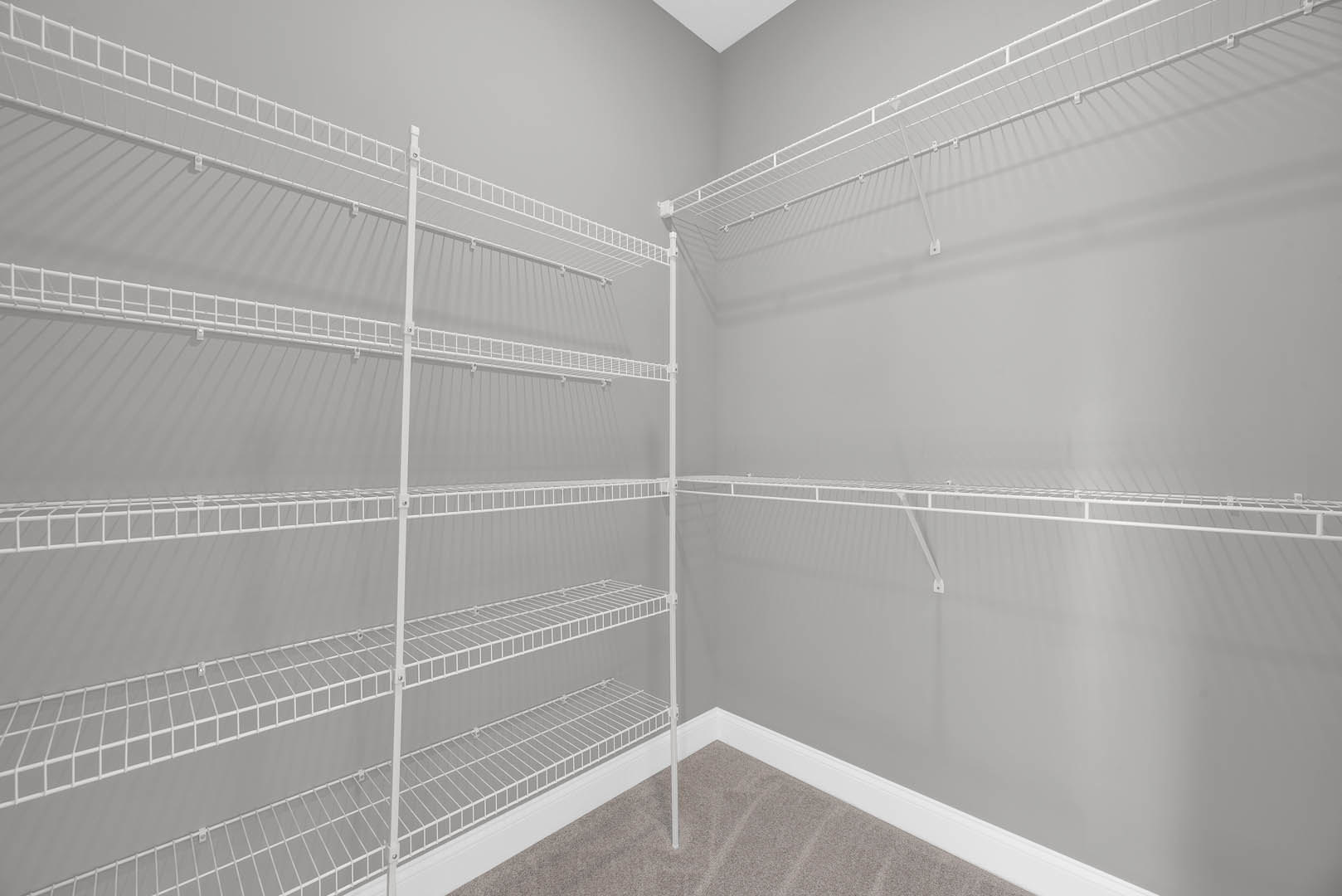 White wire shelves mounted on a wall in a room with neutral finishes.