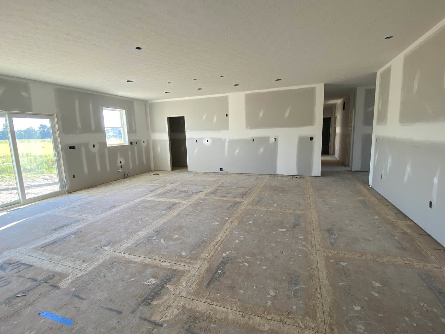 White walls with black trim, tile flooring, large window with white frame overlooking grassy field