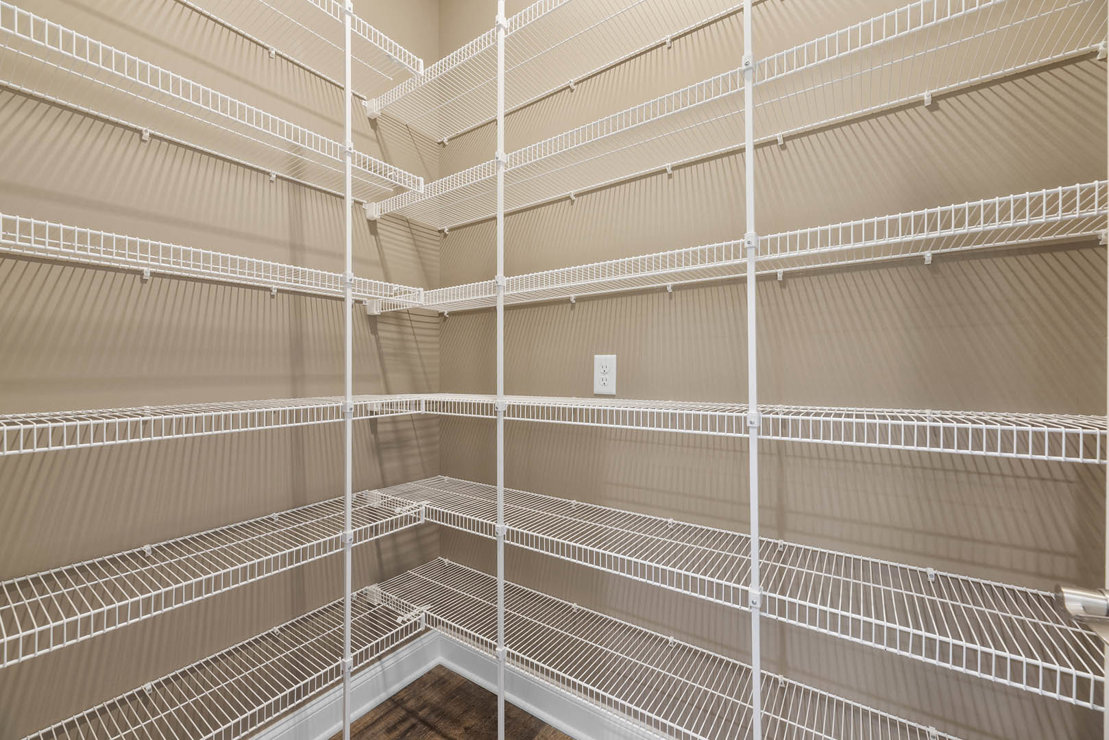 Large empty closet with white wire shelves and wooden floor