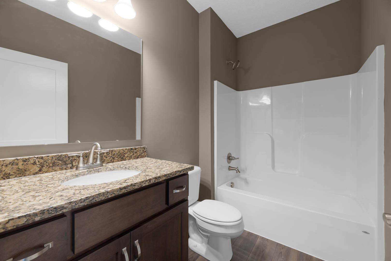 Bathroom with white tile shower, built-in sink on stone countertop, white bathtub, modern faucet, and wood cabinetry