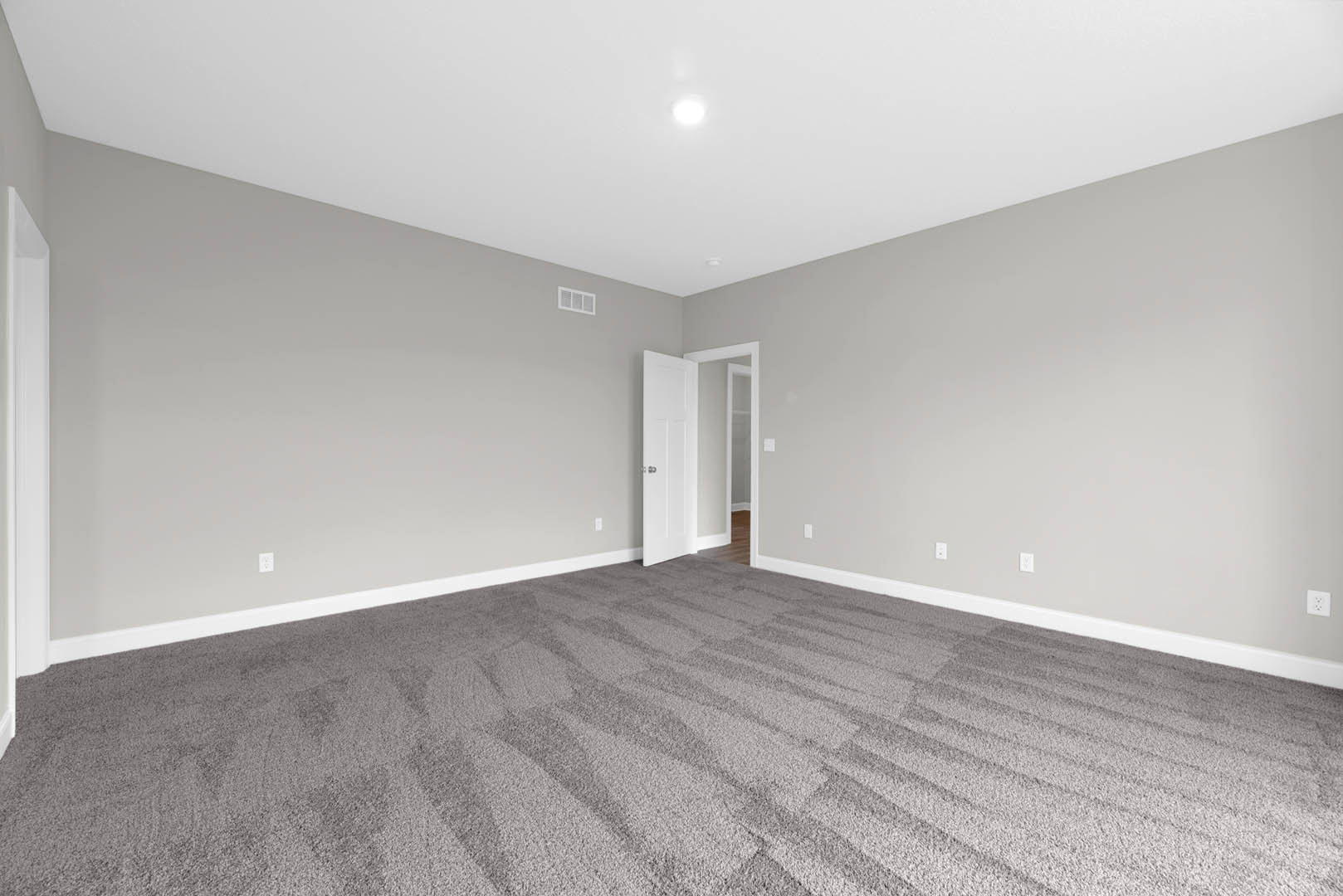 Grey carpeted floor, white door with silver knob open, white door frame, neutral walls, ceiling with recessed lighting
