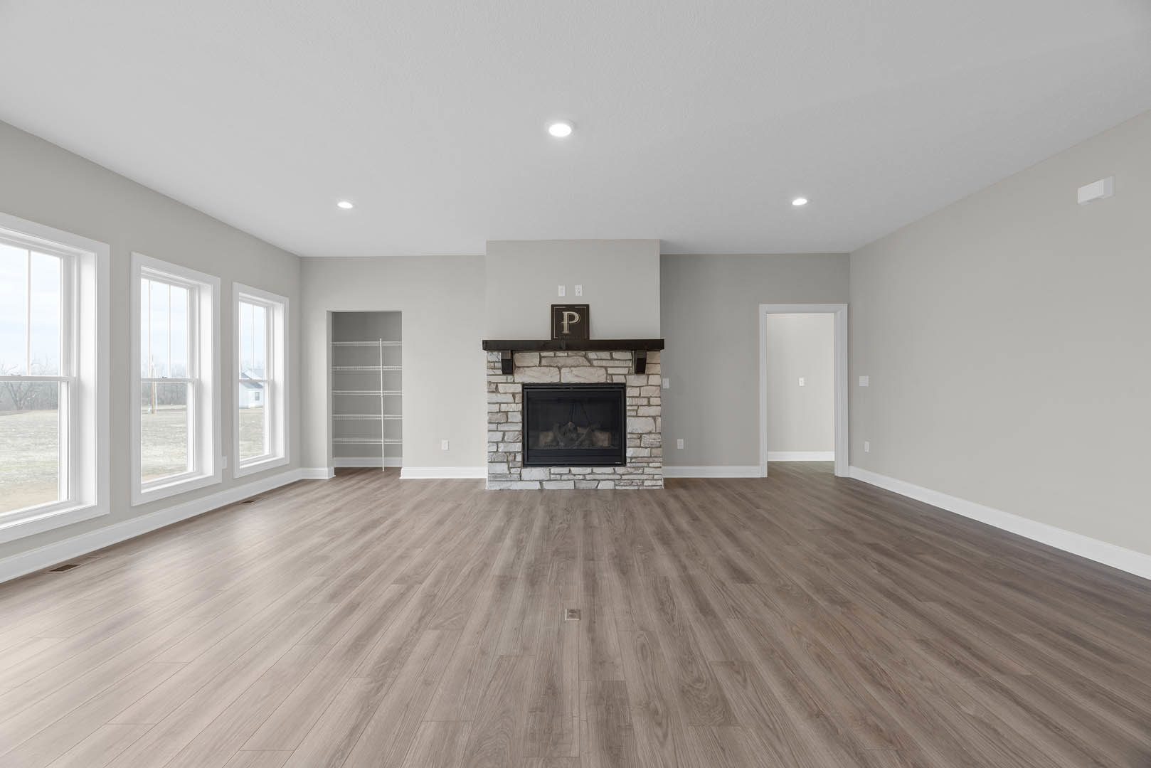 Living room with light hardwood floors, white walls, built-in white shelving, and a glass-front fireplace.
