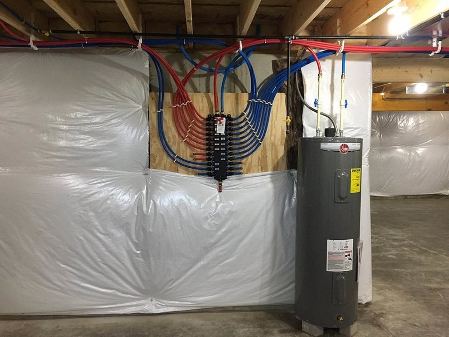 White water heater with exposed copper pipes against unfinished basement wall, concrete floor, and visible electrical wiring