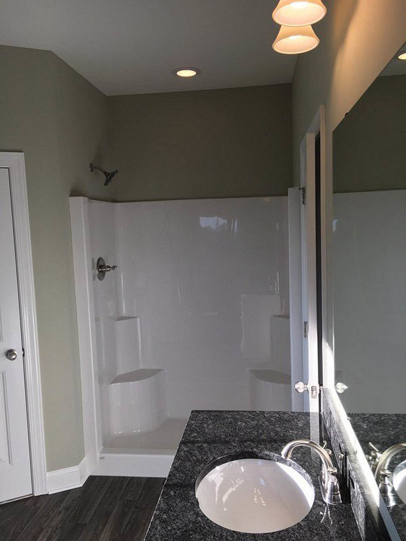 Modern bathroom featuring a marble countertop with an undermount sink, chrome faucet, glass-enclosed shower, large wall mirror, and neutral tile finishes.