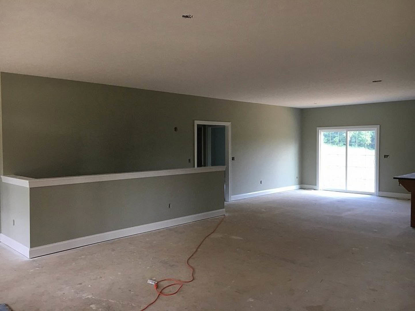 Sliding glass door set in plaster wall, red and orange cords on light flooring, partial view of table in modern interior room.