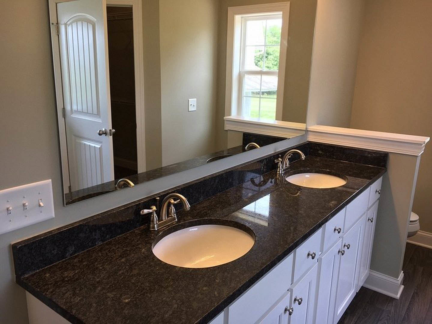 Bathroom with double sinks set in a quartz countertop, black-rimmed white vessel sinks, chrome faucets, white cabinetry, tiled backsplash, and a window providing natural light