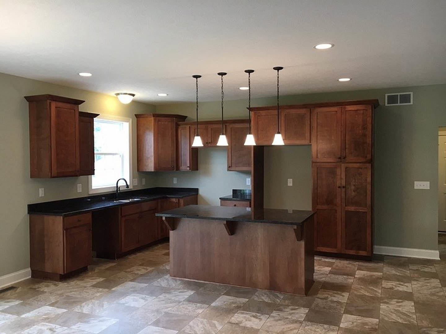 Kitchen with natural wood cabinets, granite island countertop, white-framed window, tile flooring, pendant lights, and stainless steel faucet