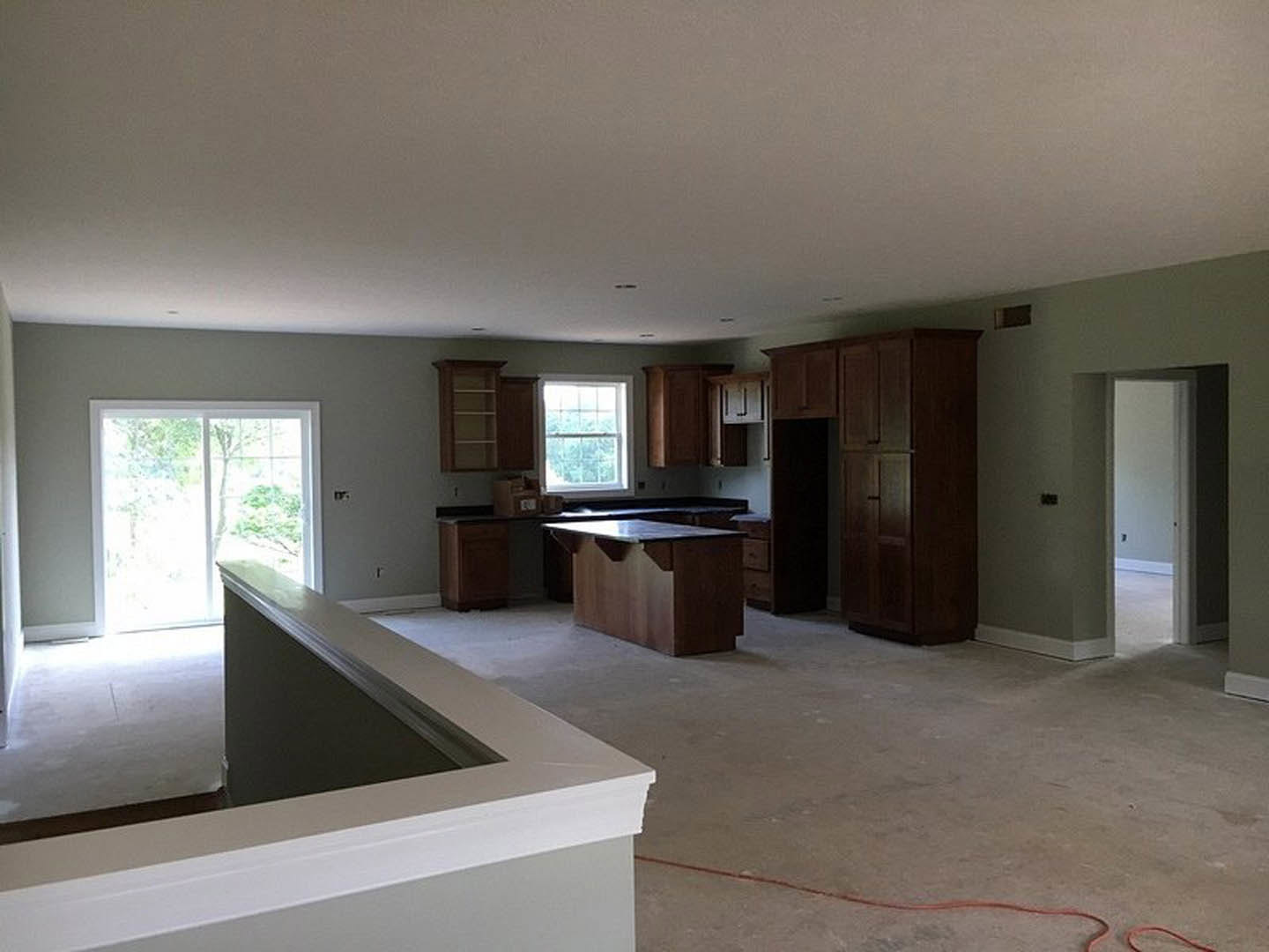 Open kitchen and dining area featuring light wood cabinetry, white countertops, large window with white frame, hardwood flooring, and recessed ceiling lights.