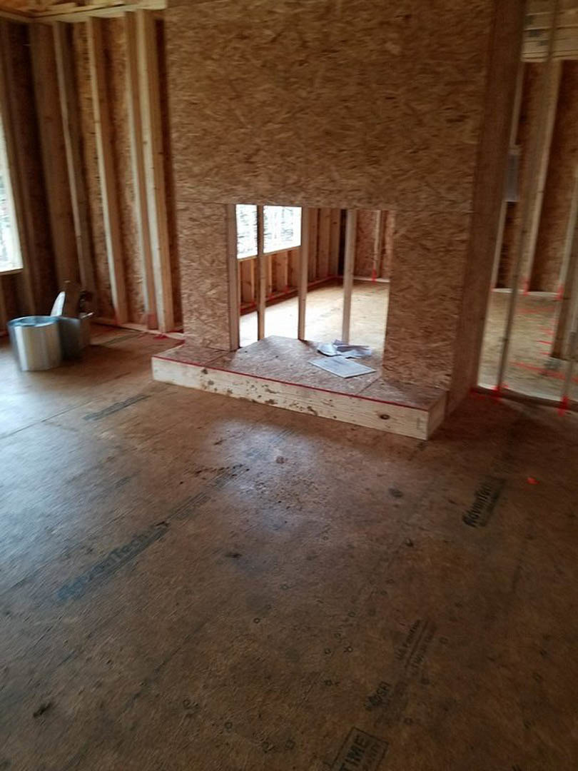 Wood-paneled walls and large windows in a residential room, natural light illuminating hardwood flooring and plaster ceiling