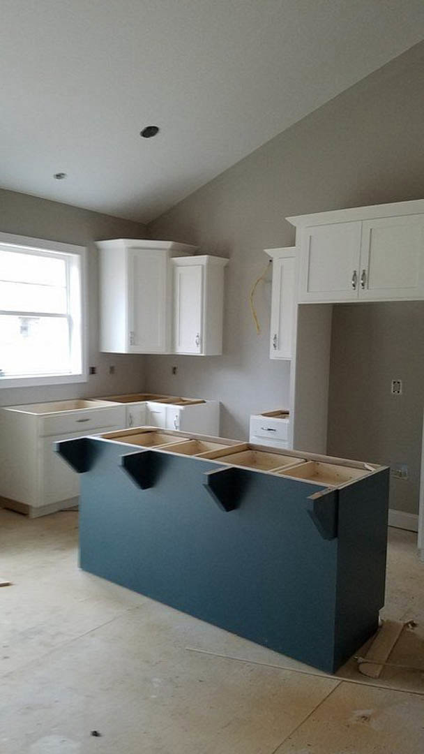 Kitchen featuring white shaker cabinets, blue island with white quartz countertop, stainless steel sink, brushed nickel hardware, light wood flooring, and recessed ceiling lights