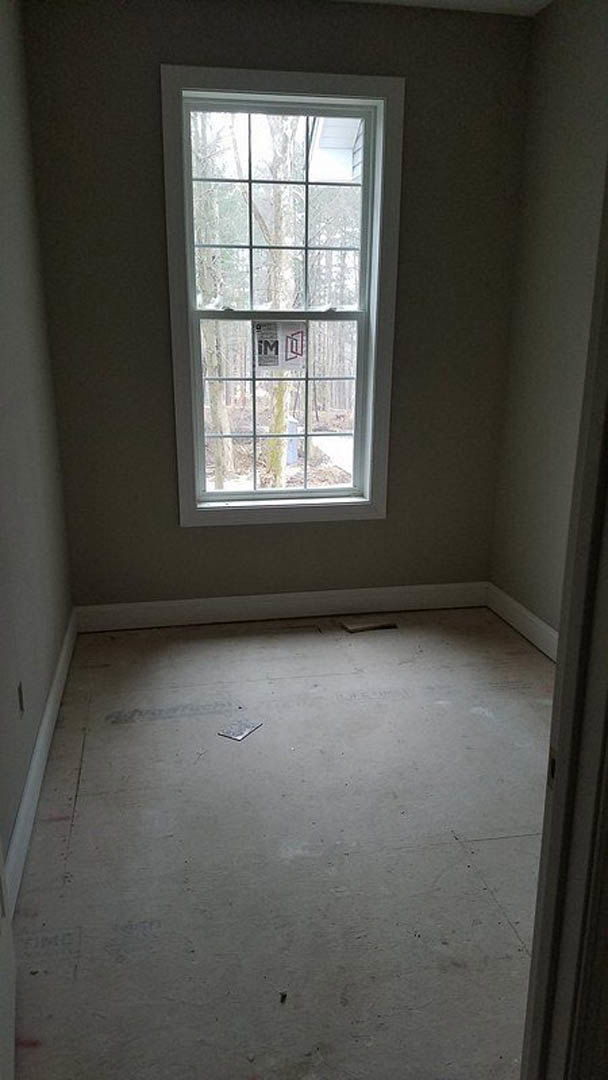 Sunlit room with large window, smooth plaster walls, and polished wood flooring