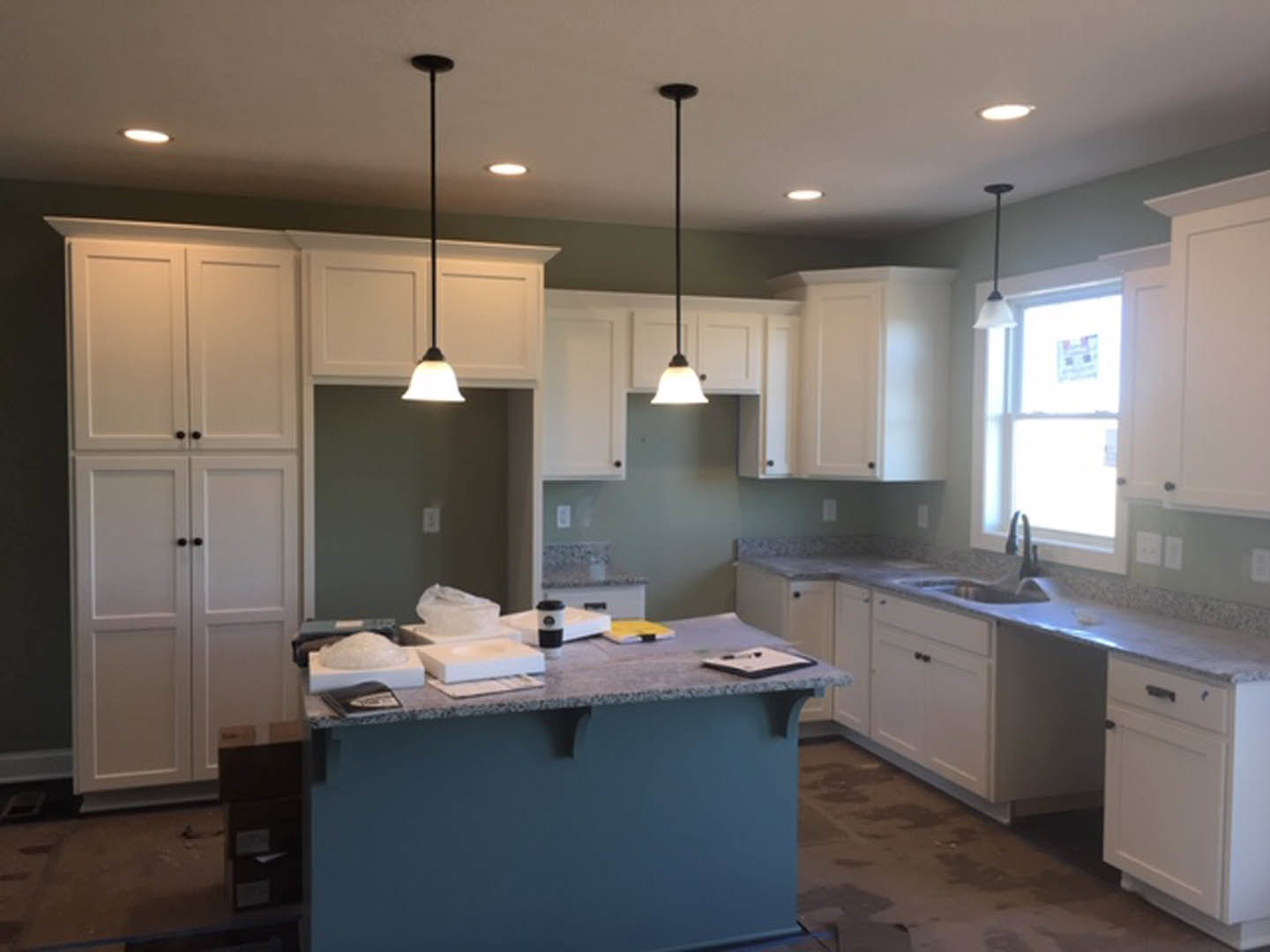 White kitchen cabinets with brushed nickel hardware, light stone countertop, stainless steel sink, and neutral painted walls