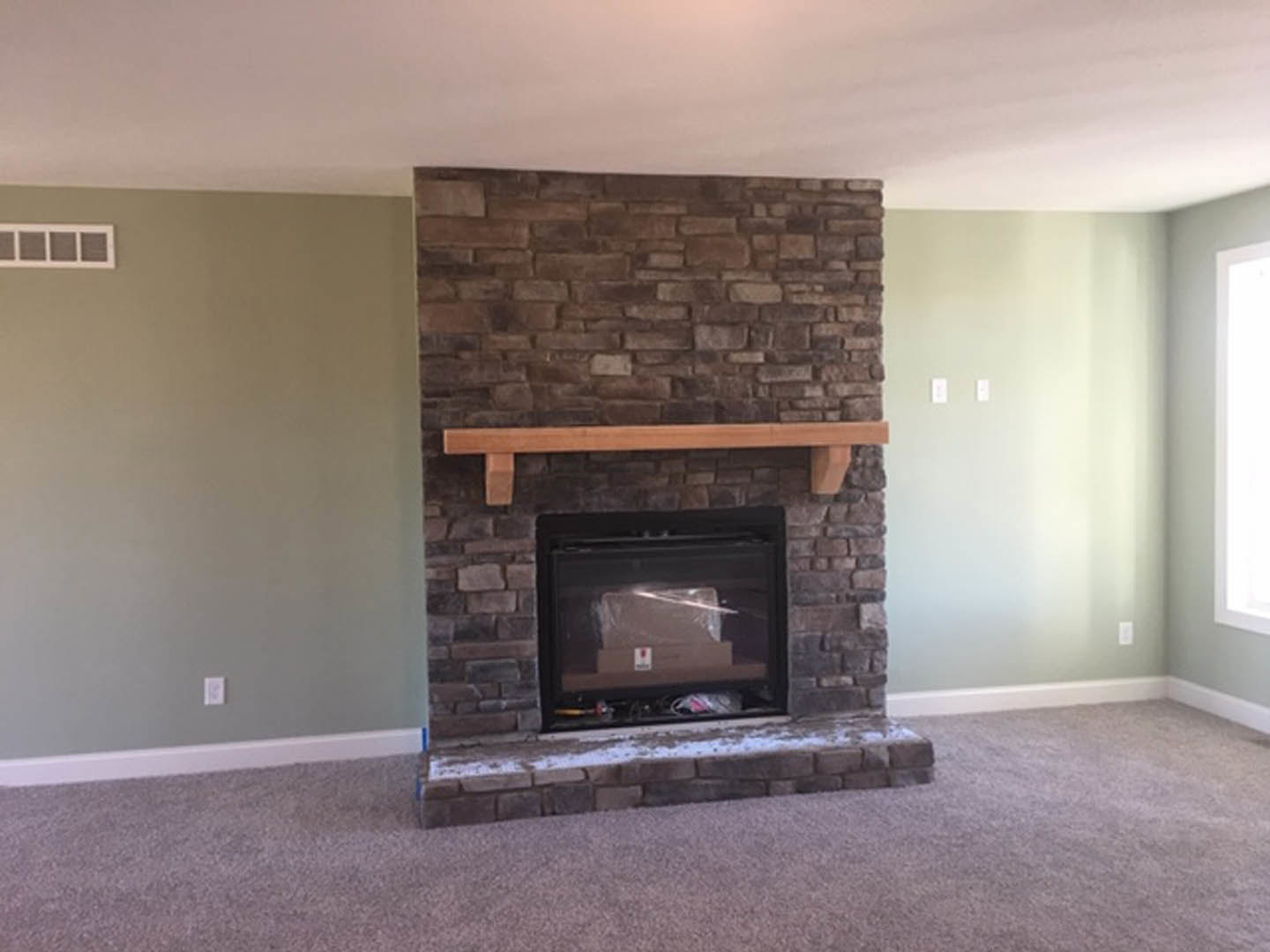 Brick fireplace with wooden mantel, glass door fire screen, and white walls in a modern living room.