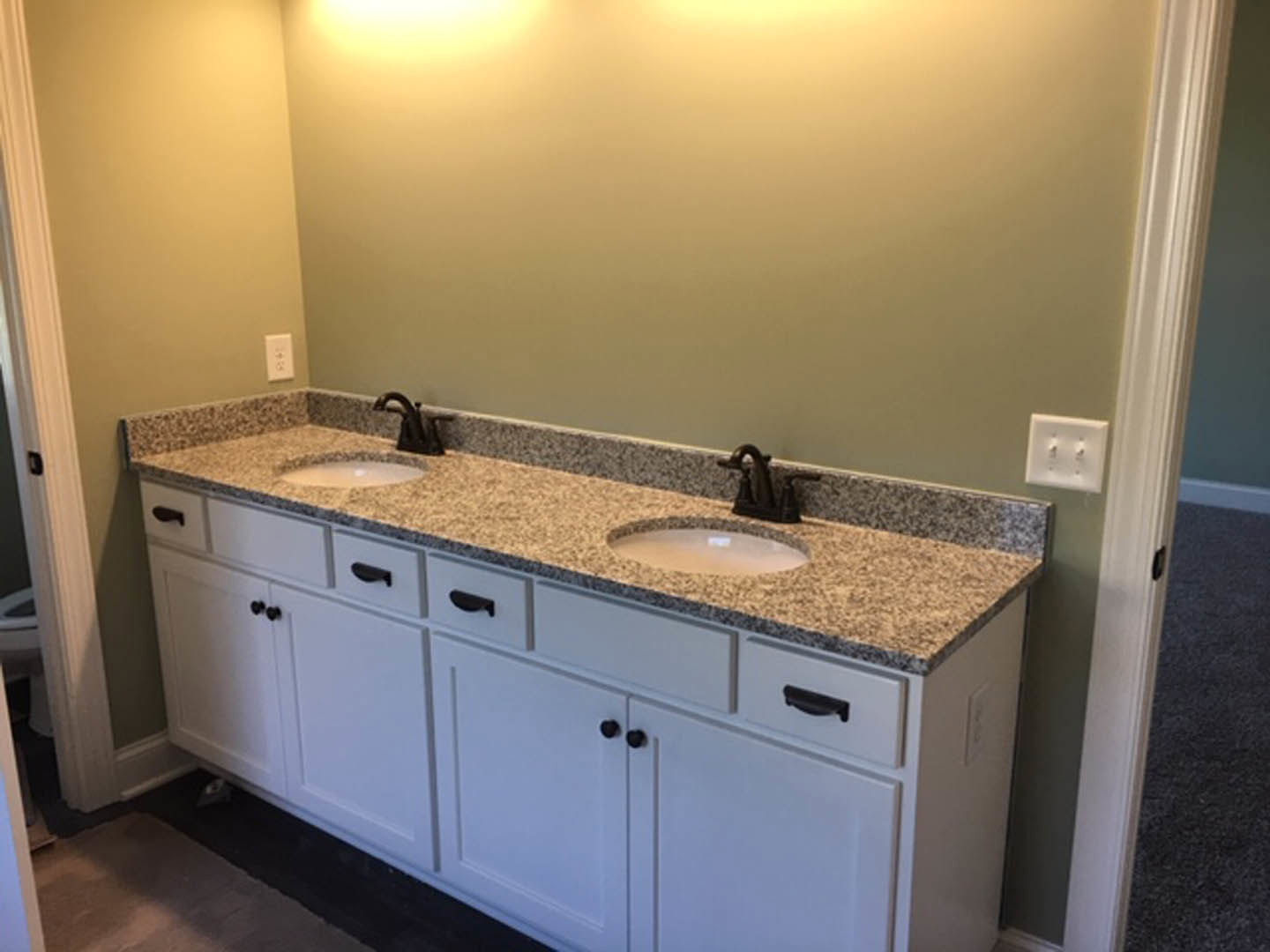 Double vanity bathroom with white sinks, light wood cabinets, stone countertop, chrome faucets, and neutral tile backsplash