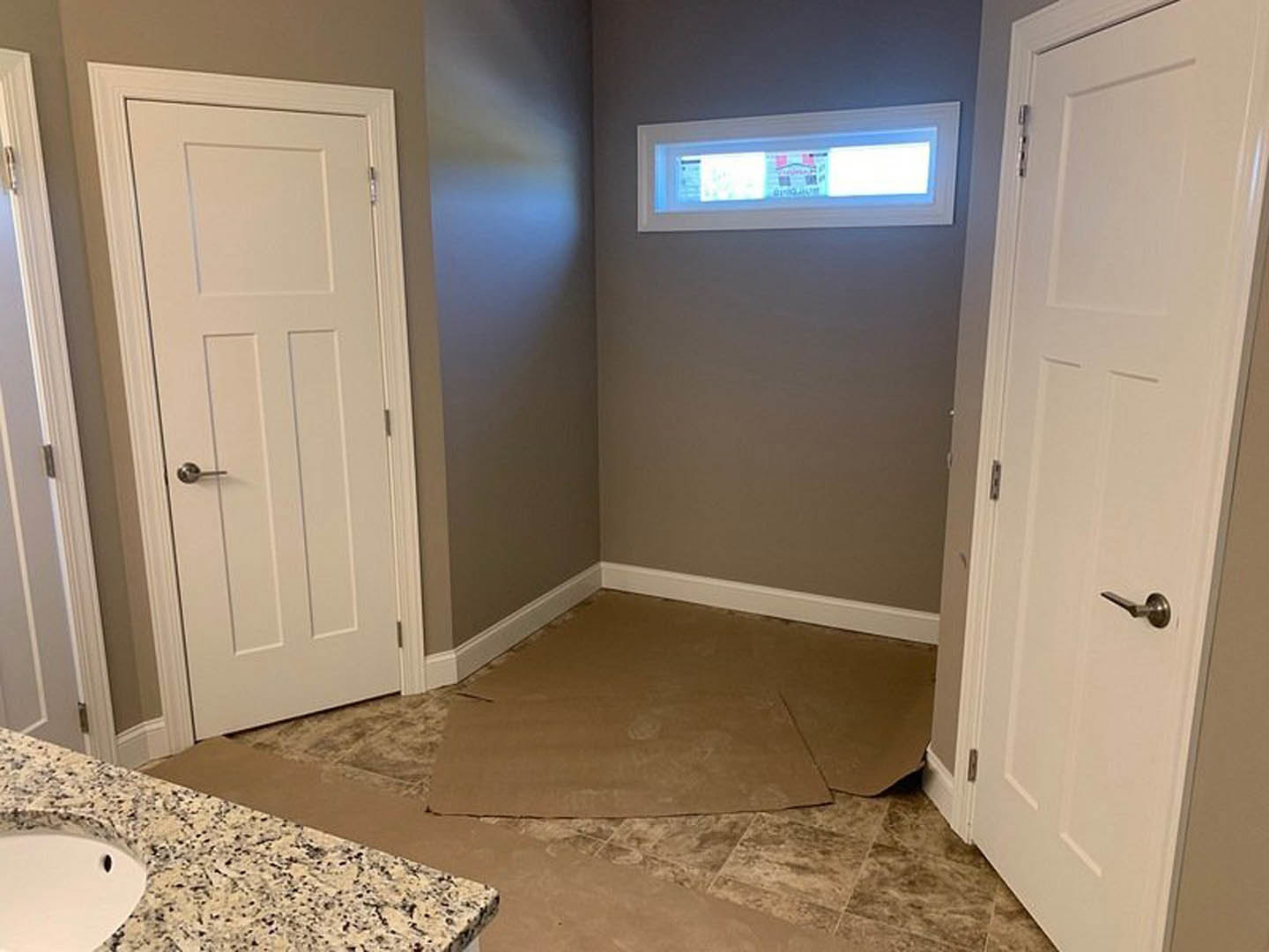 Bathroom with marbled tile floor, white door featuring silver handle, white sink, plaster walls, and window providing natural light